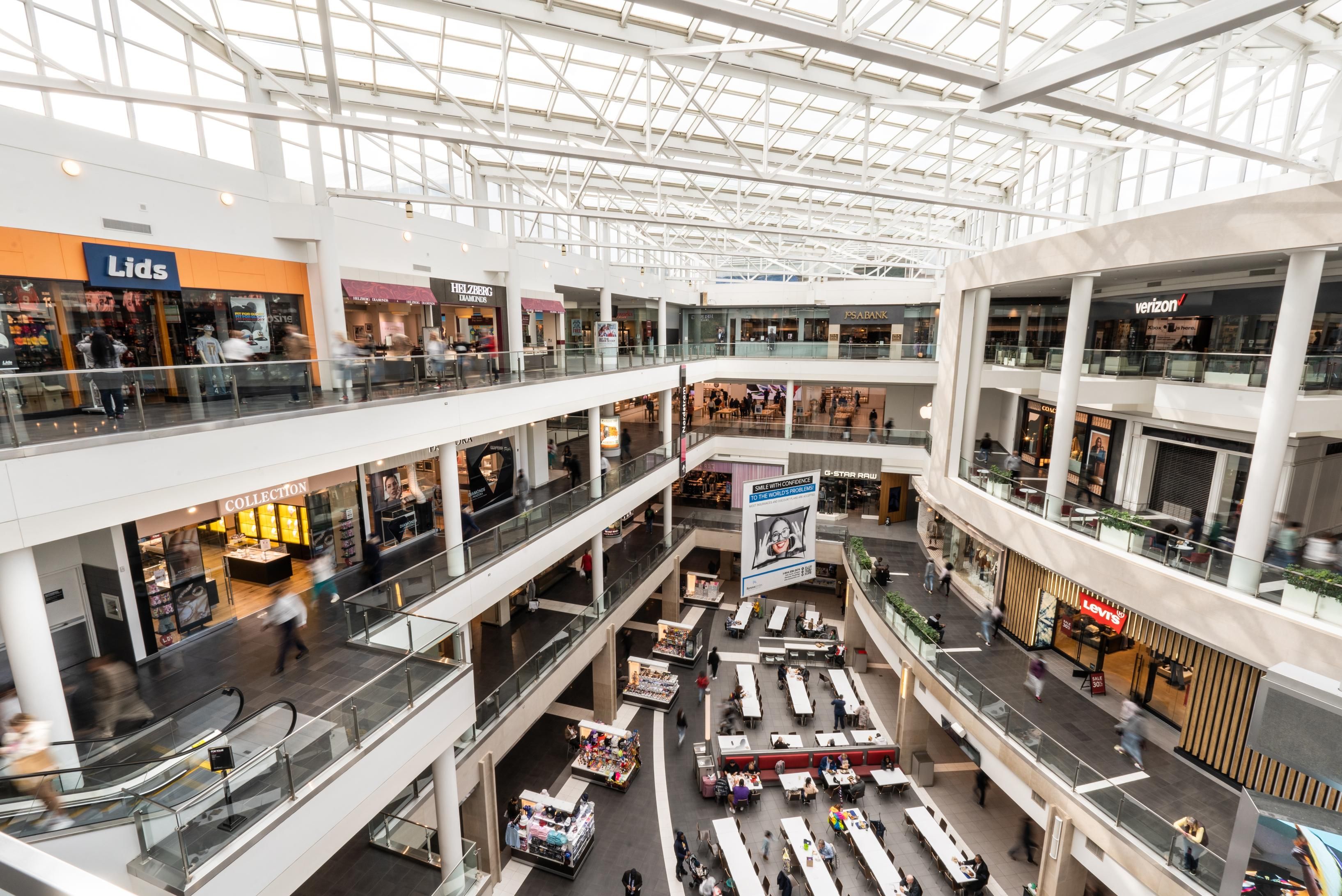 Interior view of a multi-level shopping mall with stores and shoppers.