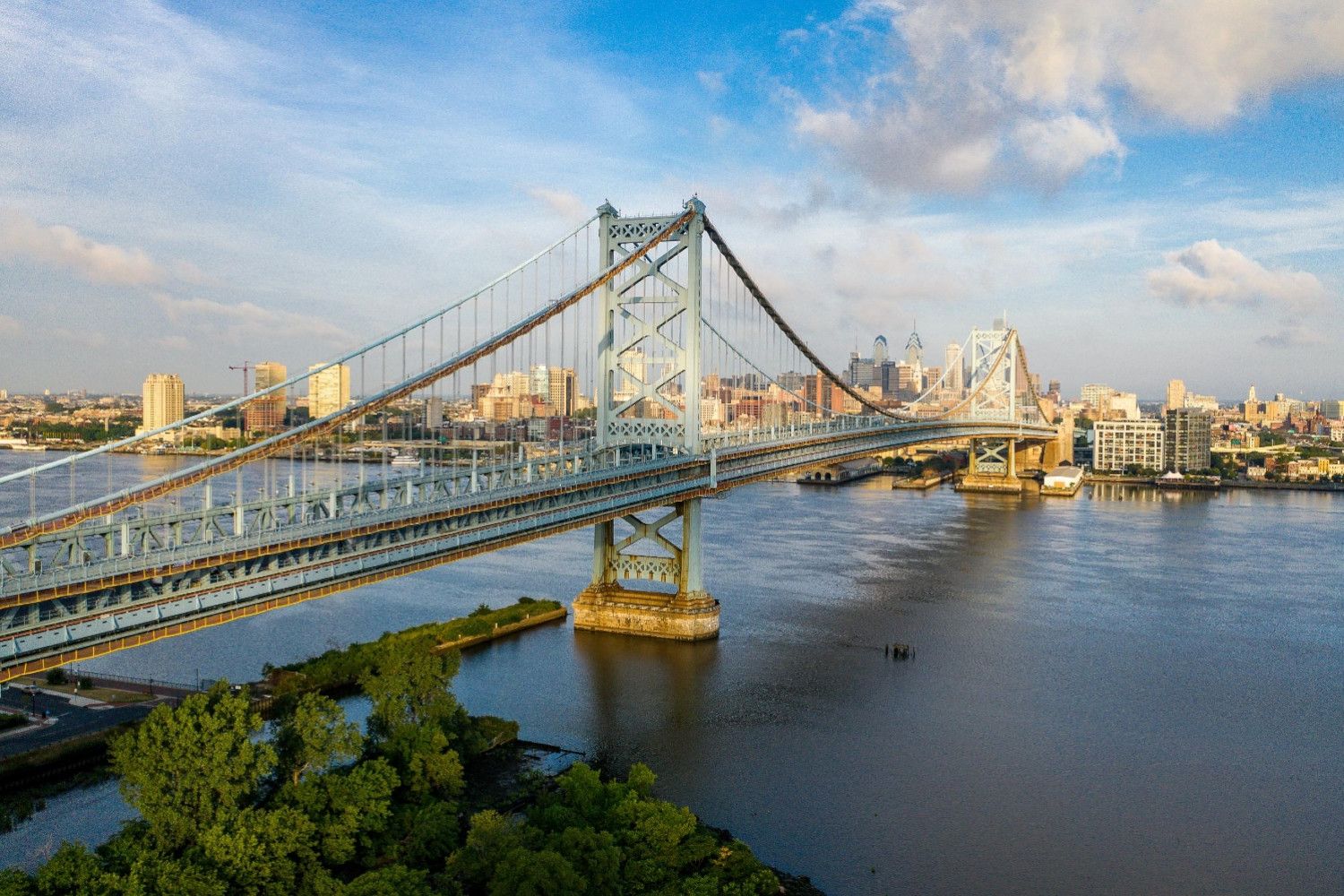 Aerial view of a bridge over a river with a city skyline in the background.