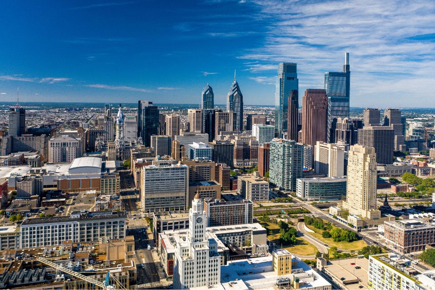 Aerial view of a modern city skyline with skyscrapers under a blue sky.