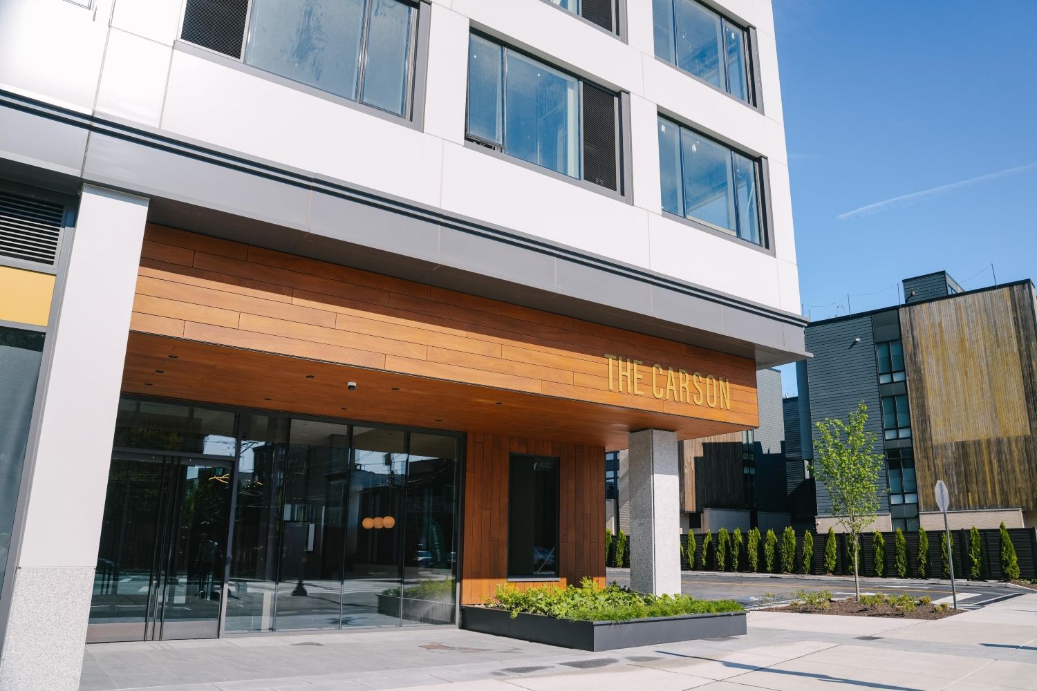 Modern building entrance with large windows and a wooden awning.