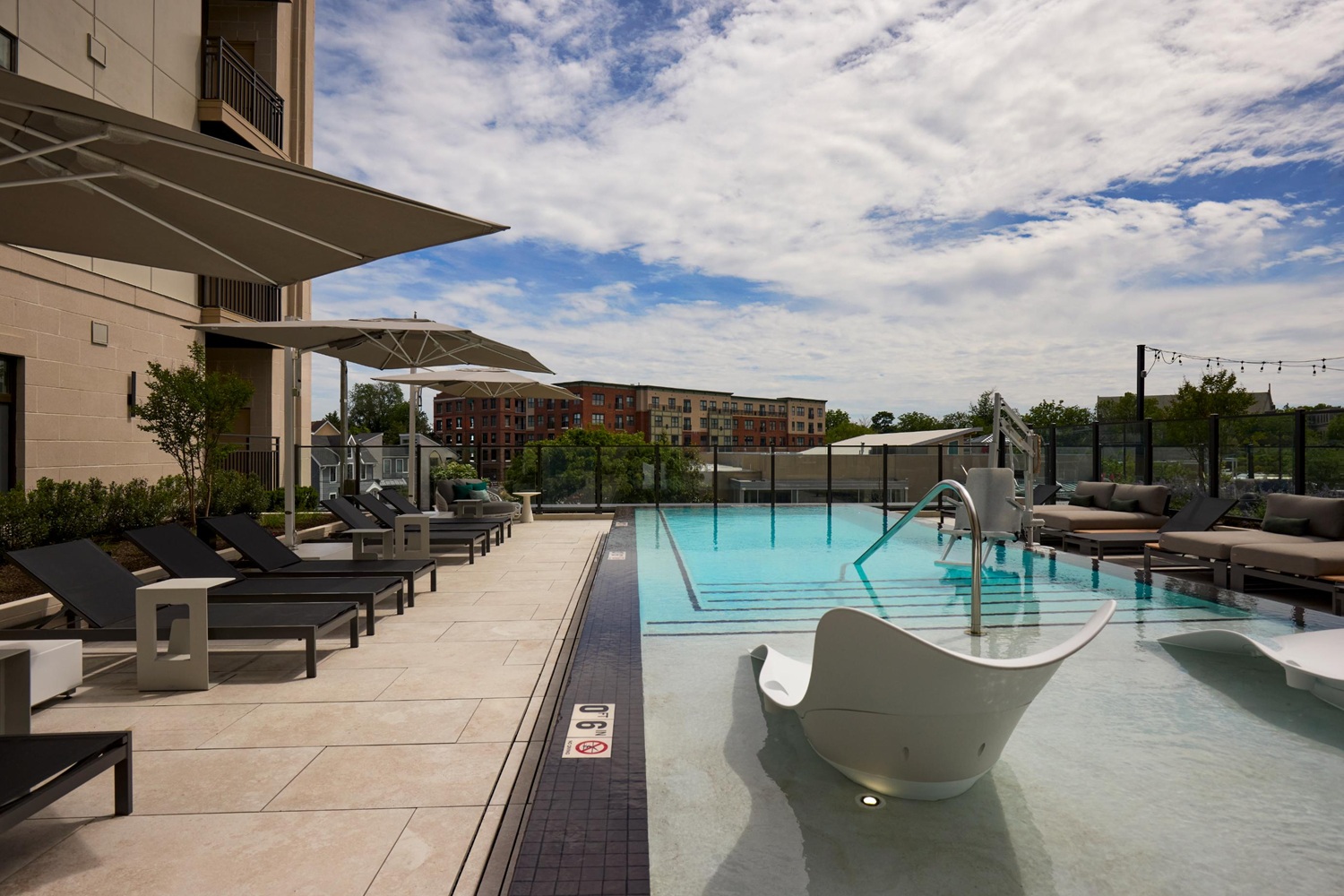 Resort-style poolside living with lounge seating, shade, and skyline views