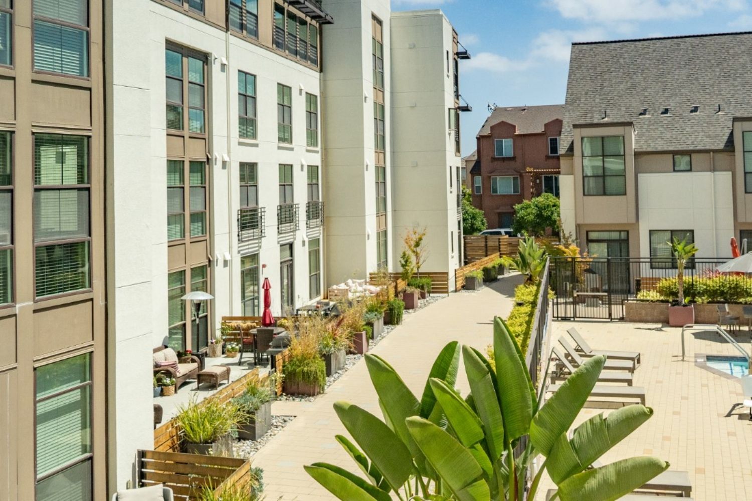 Modern apartment complex courtyard with greenery and a swimming pool.