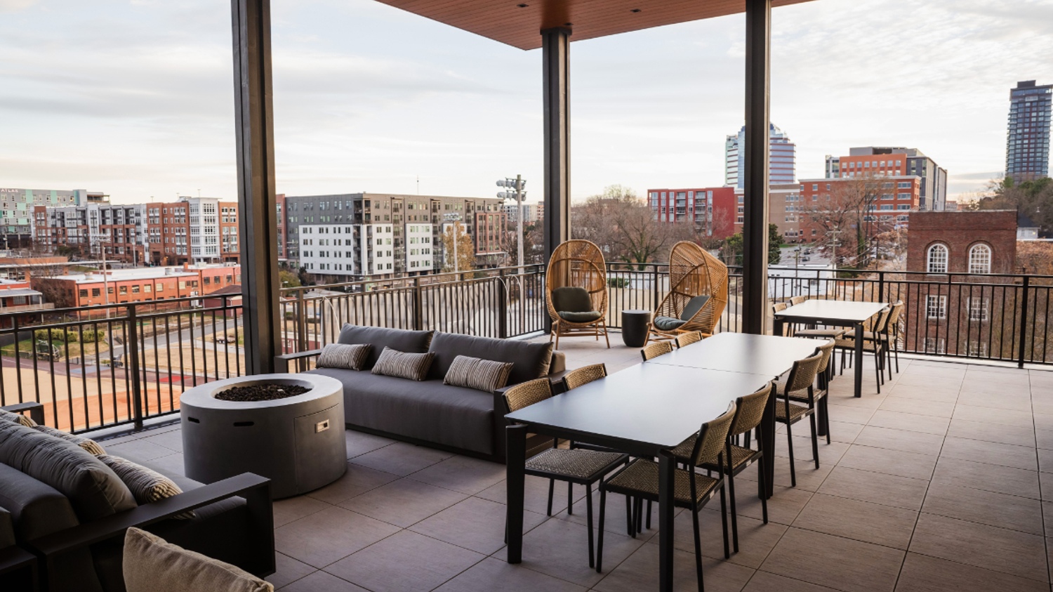 Modern outdoor patio with a dining table, seating area, and cityscape view.