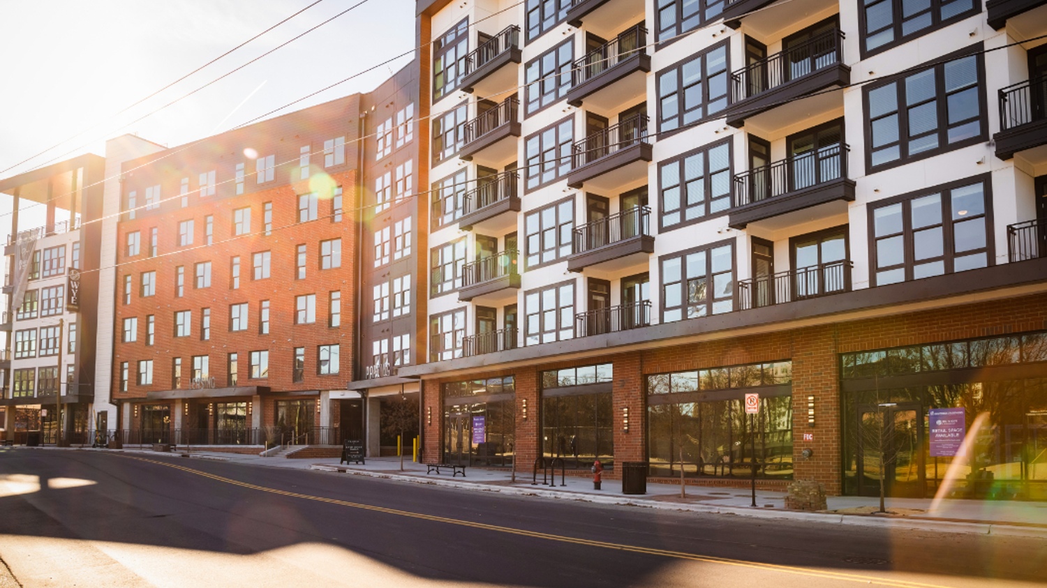Modern apartment buildings with large windows and vibrant facade under bright sunlight.