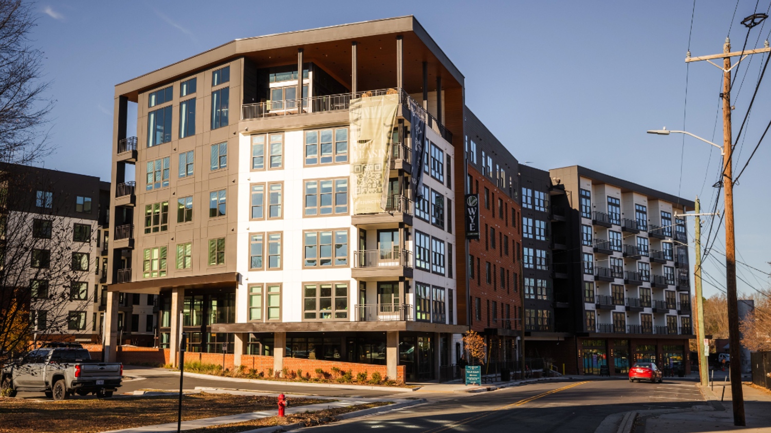 Modern multi-story buildings at a street intersection under clear blue skies.