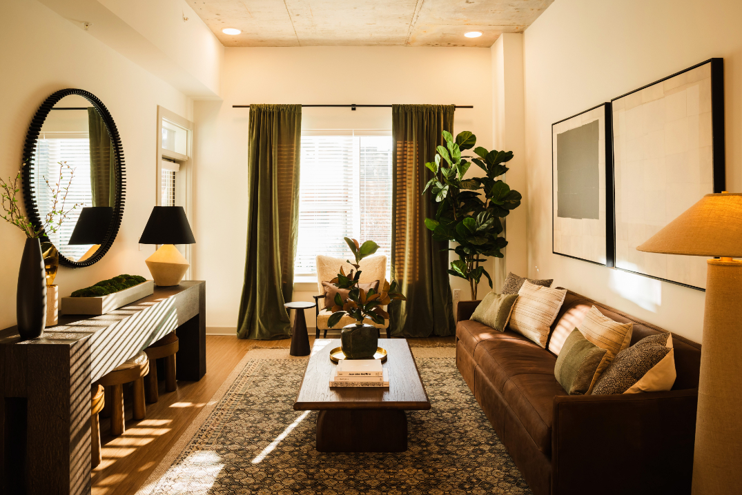 Stylish living room with brown sofa, green curtains, and decorative plants.