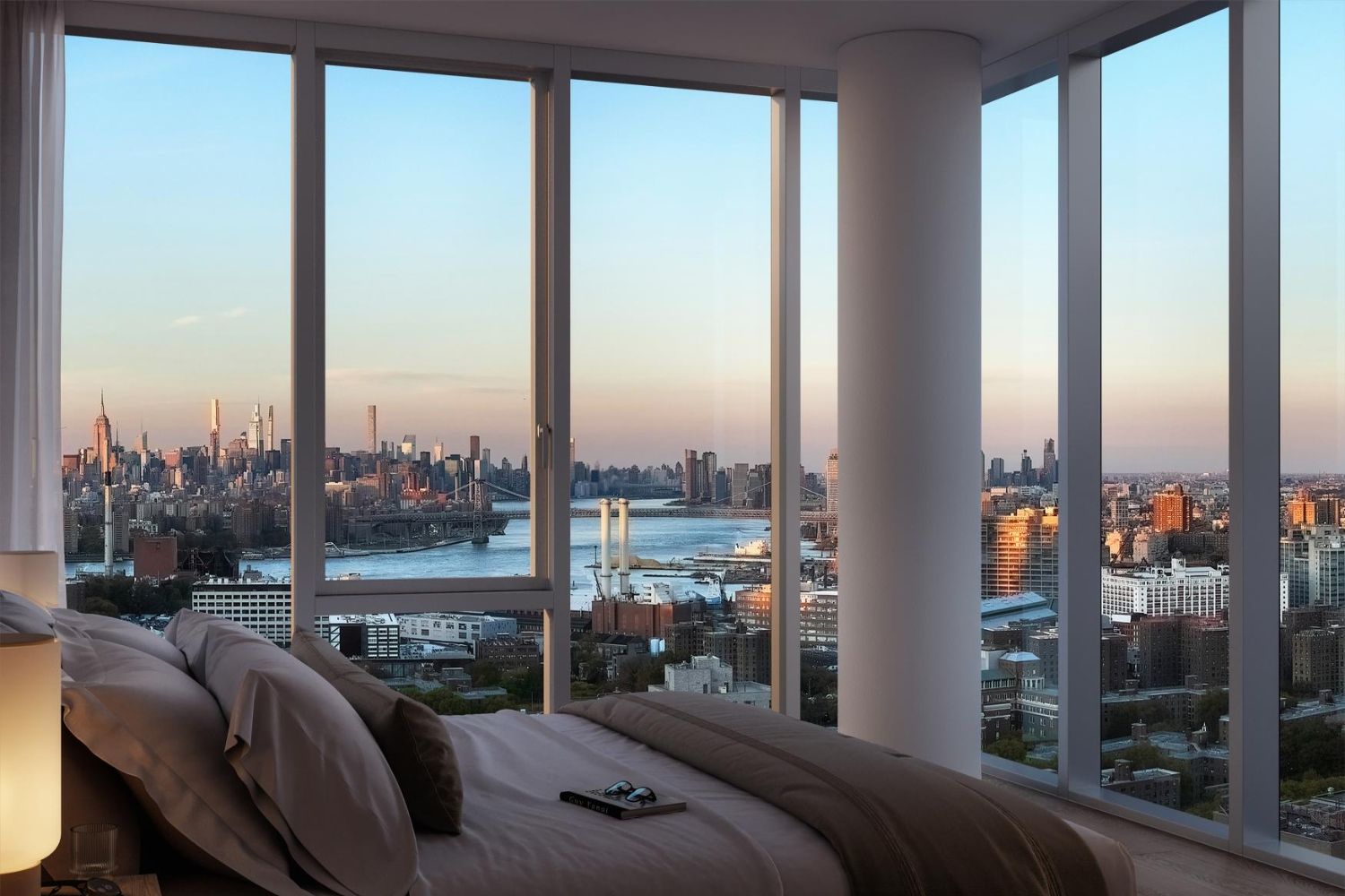 Modern bedroom with large windows overlooking a city skyline at sunset.
