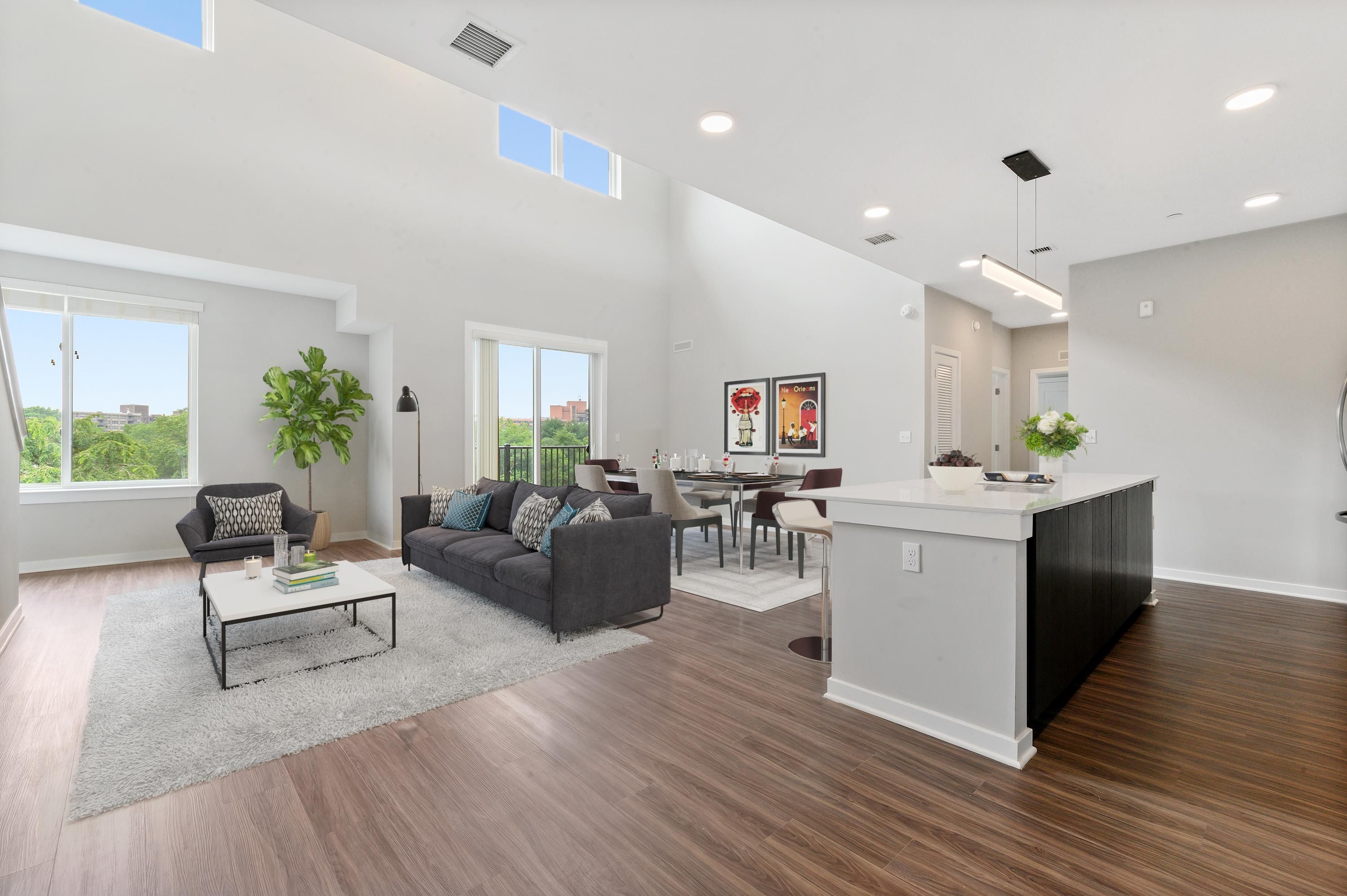 Spacious modern open-concept living area with a kitchen, dining table, and large windows.