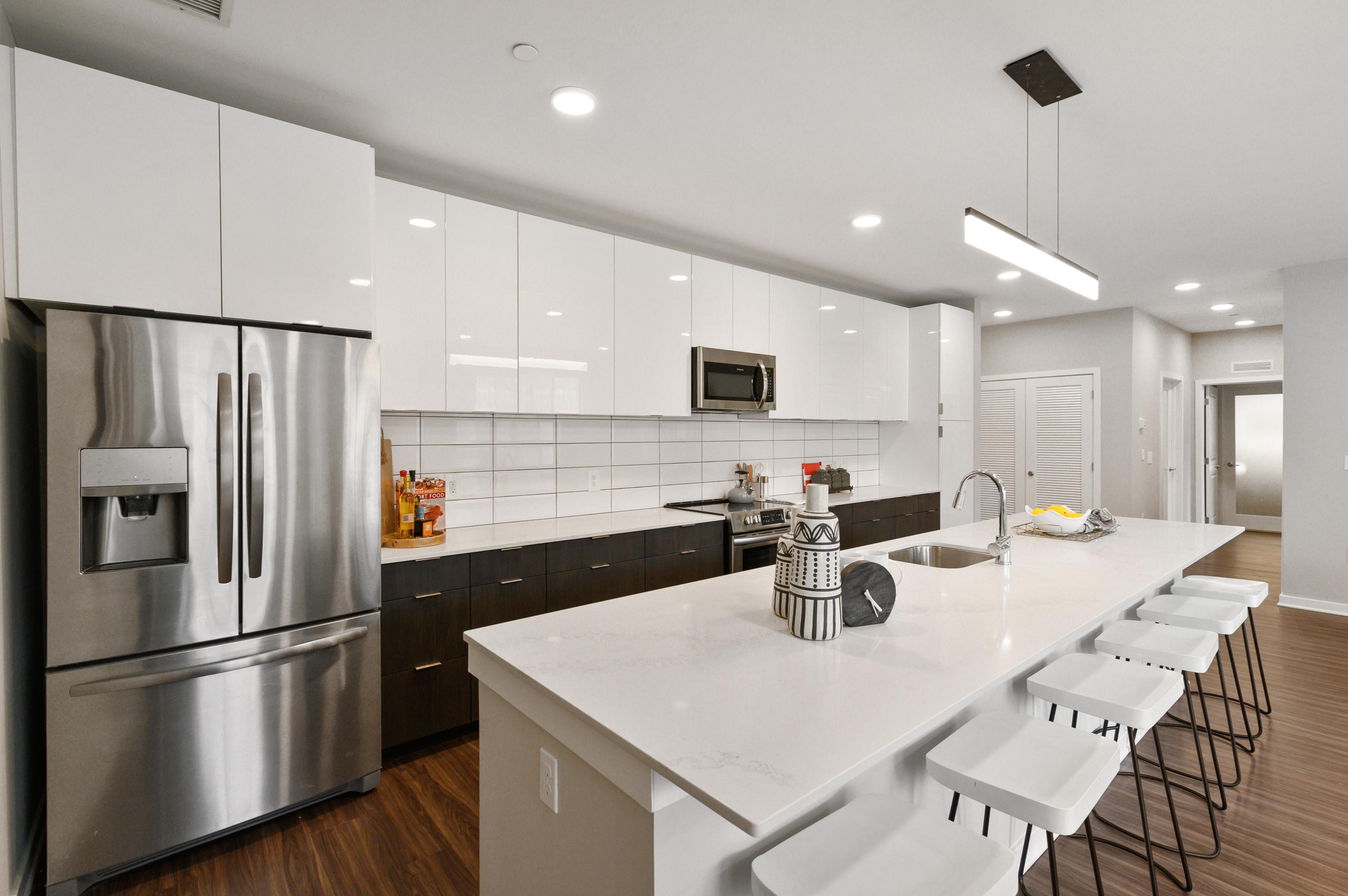 Modern kitchen with white cabinets, stainless steel appliances, and a large island.