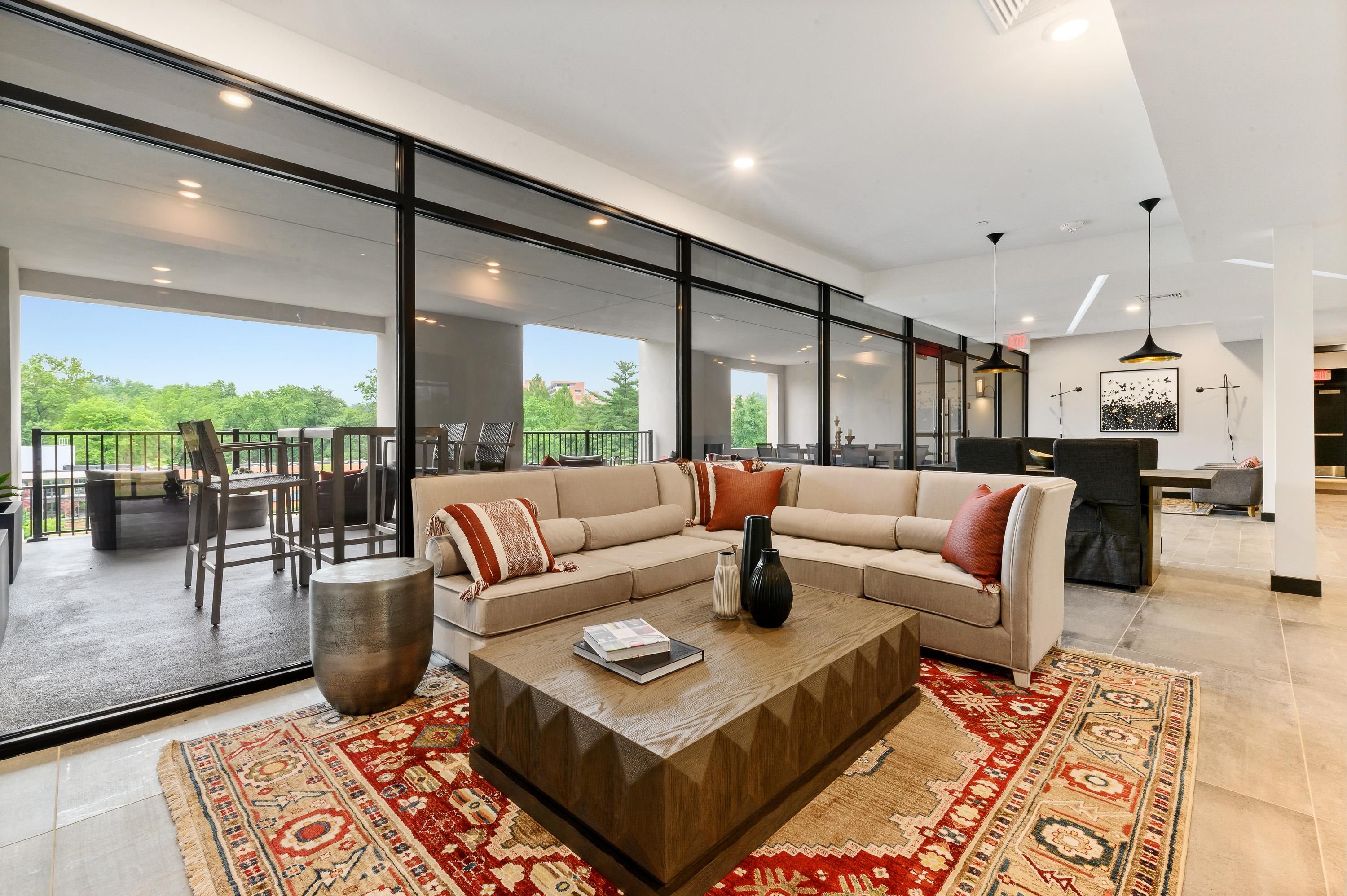 Modern living room with a sectional sofa, coffee table, and large windows overlooking greenery.