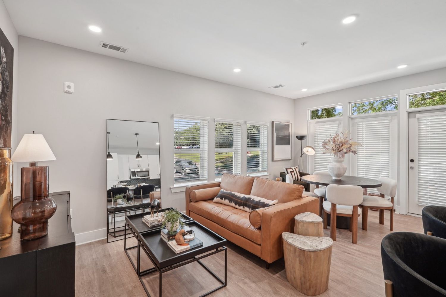 Cozy living room with a leather sofa, table, and large windows letting in natural light.