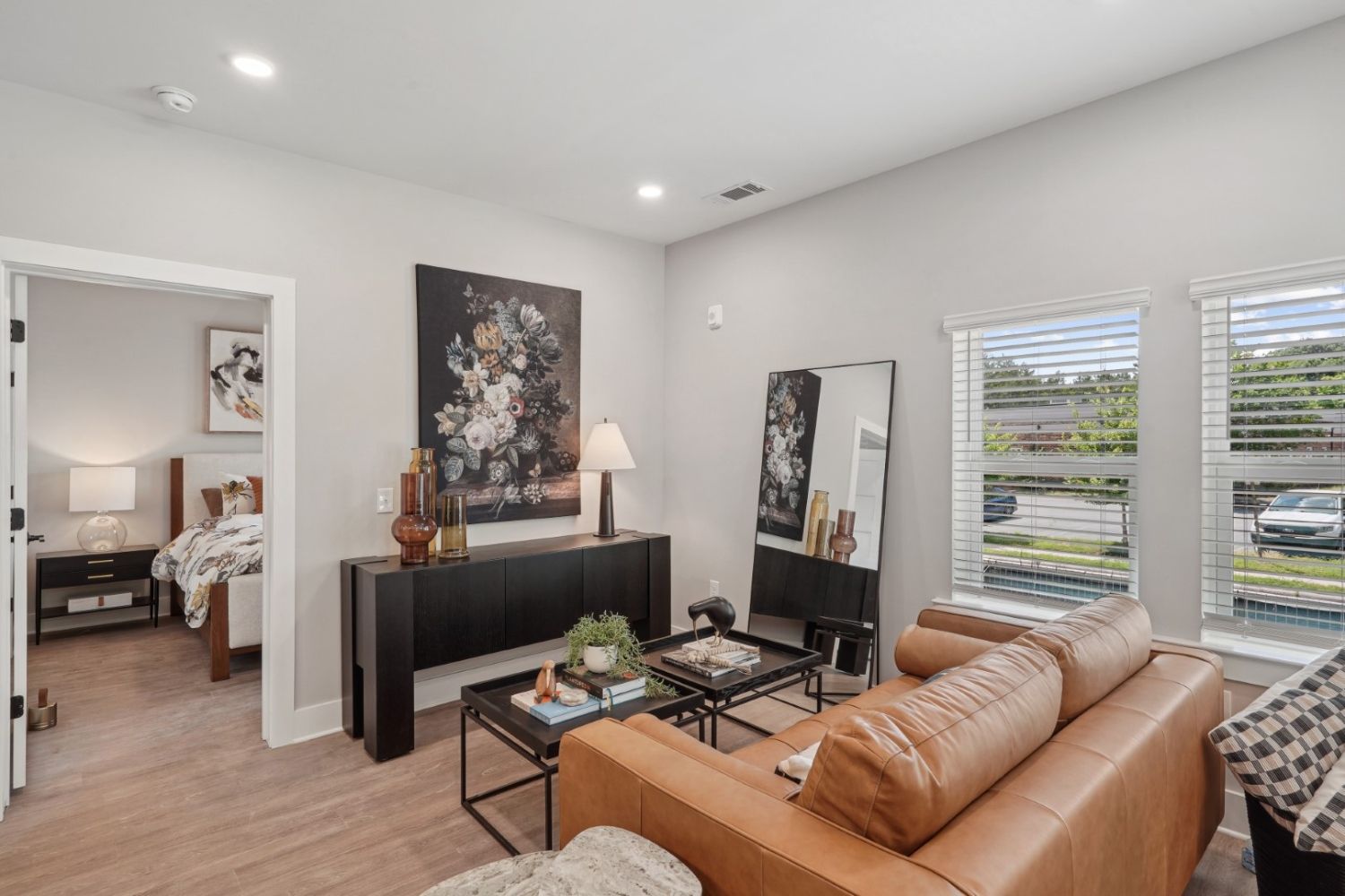 Modern living room with a brown sofa, artwork, and large windows.