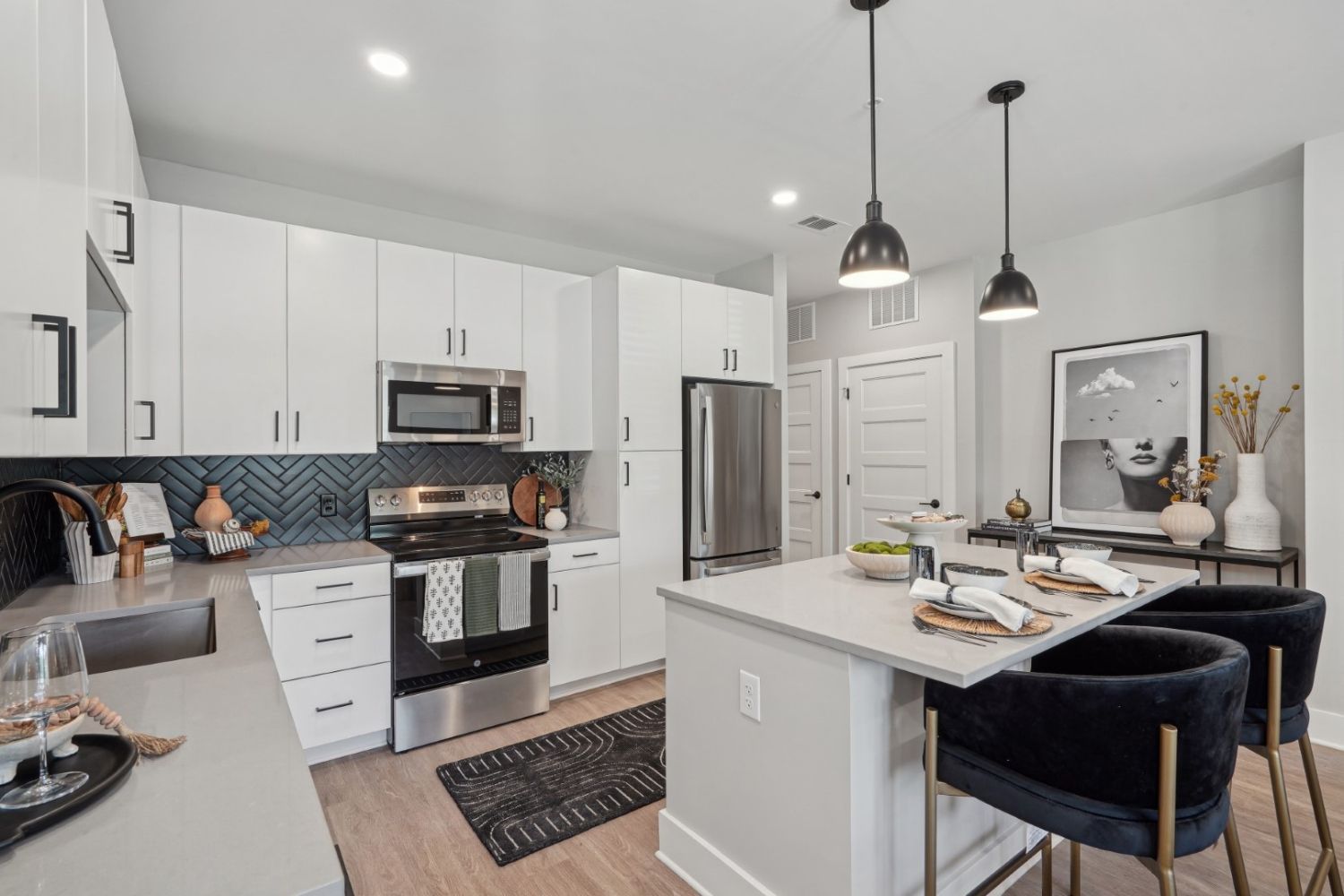Modern kitchen with white cabinets, stainless steel appliances, and a breakfast bar.