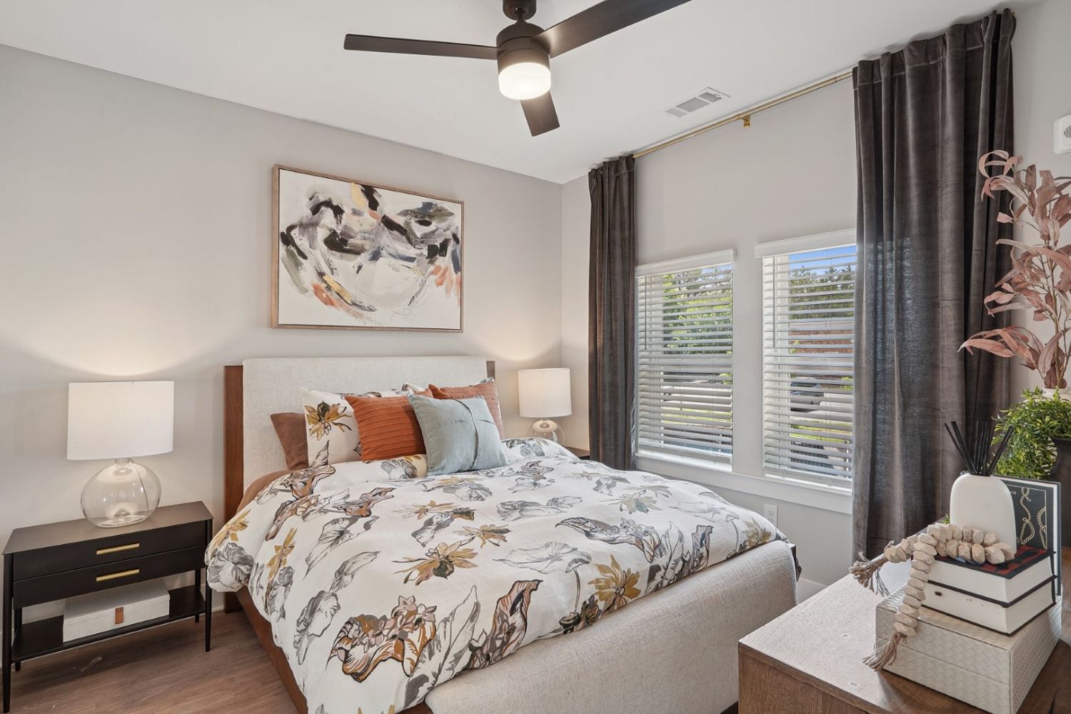 Cozy bedroom with a floral duvet, two lamps, a window, and modern decor.