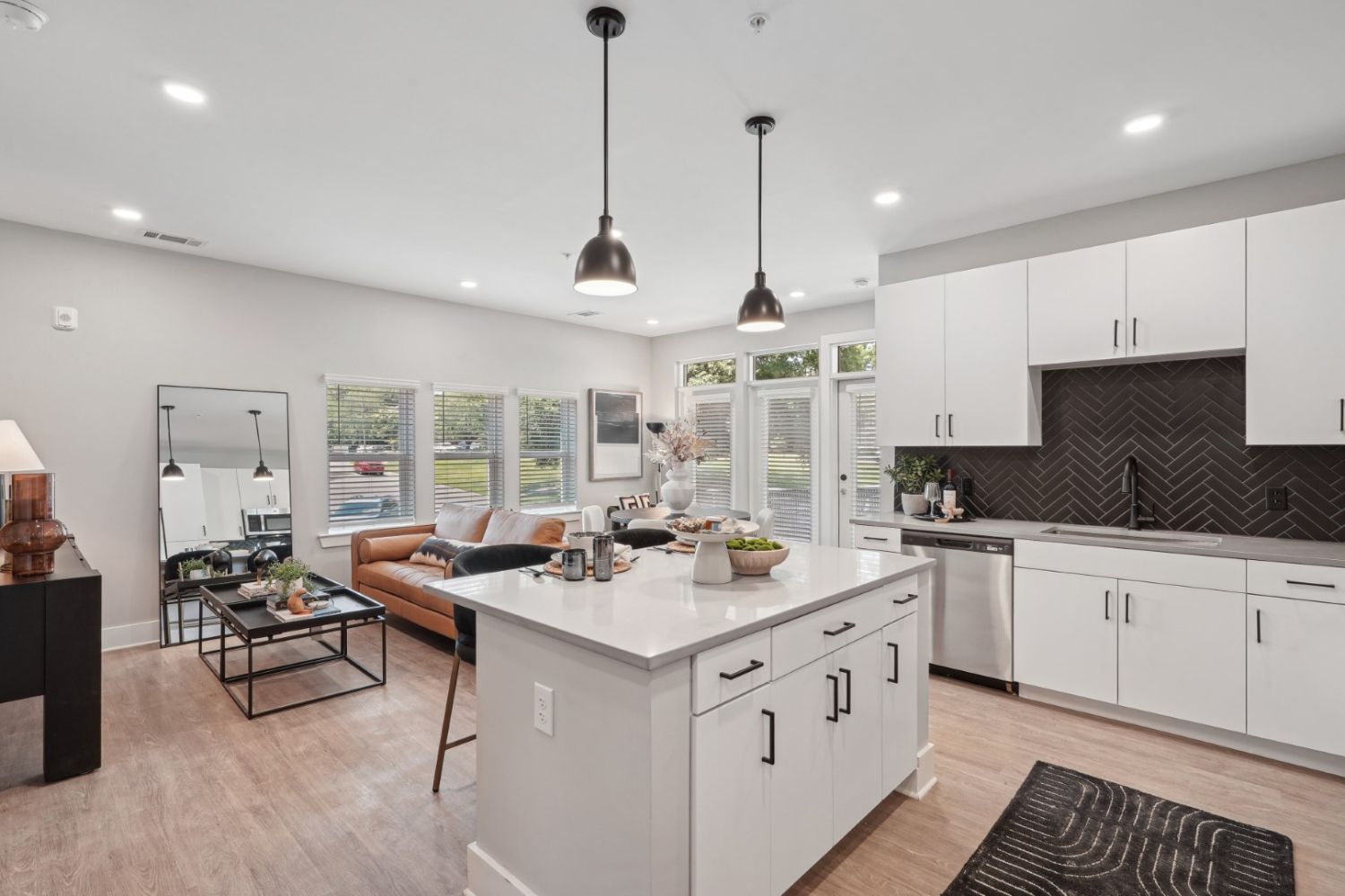 Modern kitchen and living area with pendant lights and large windows.