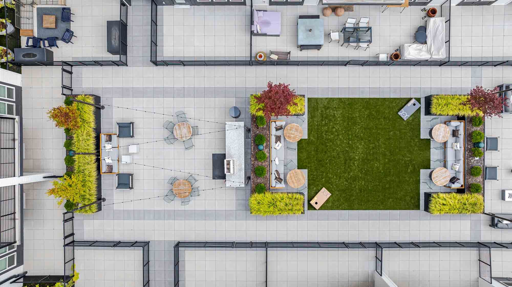 Aerial view of a modern rooftop terrace with greenery and seating areas.