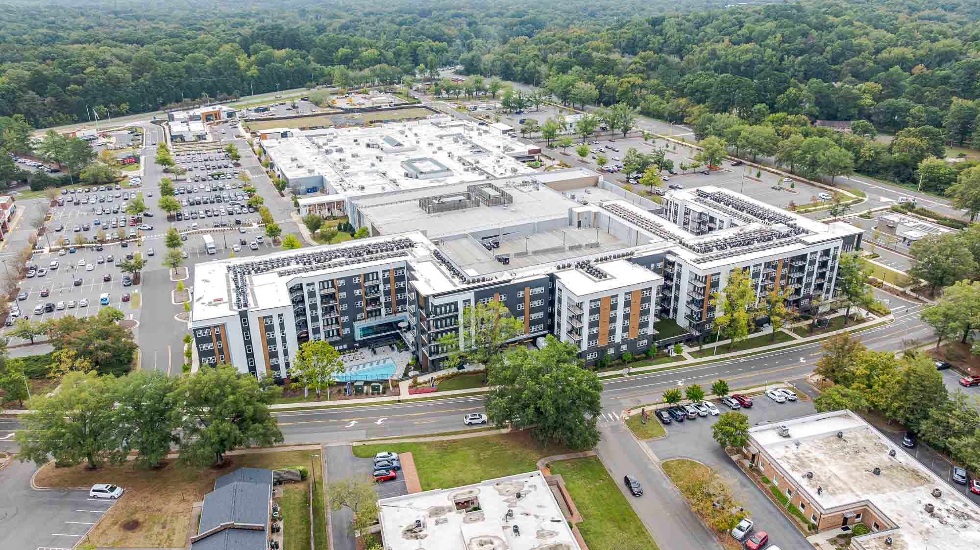Aerial view of a modern apartment complex surrounded by parking and greenery.