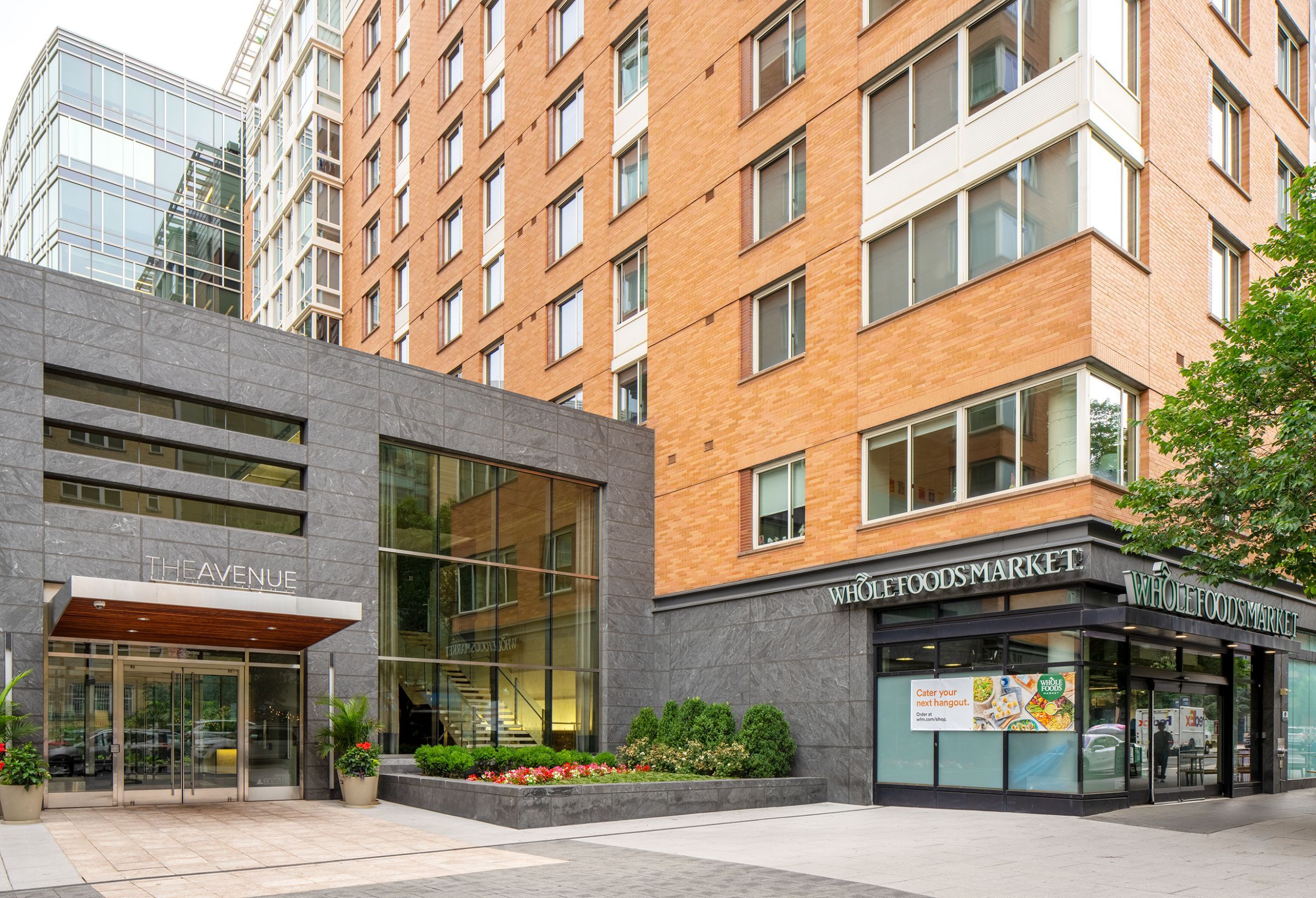 Modern building entrance with glass facade and brick exterior in an urban setting.