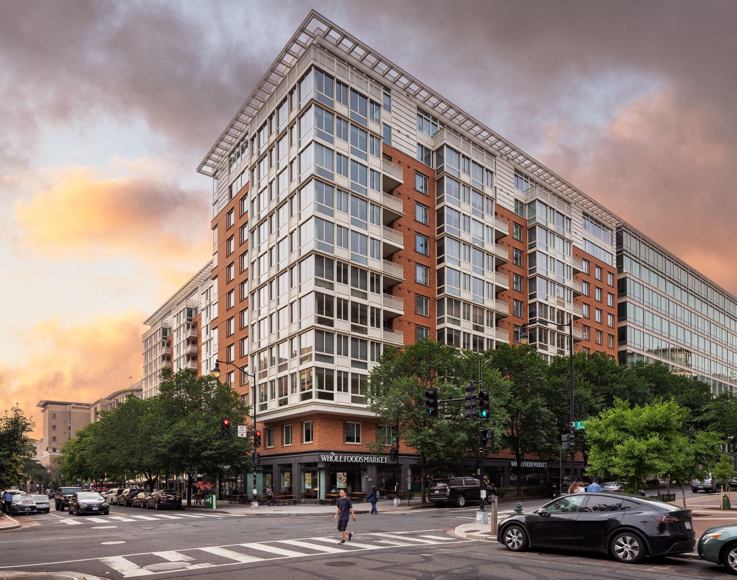 Modern urban building at sunset with cloudy sky and busy street.