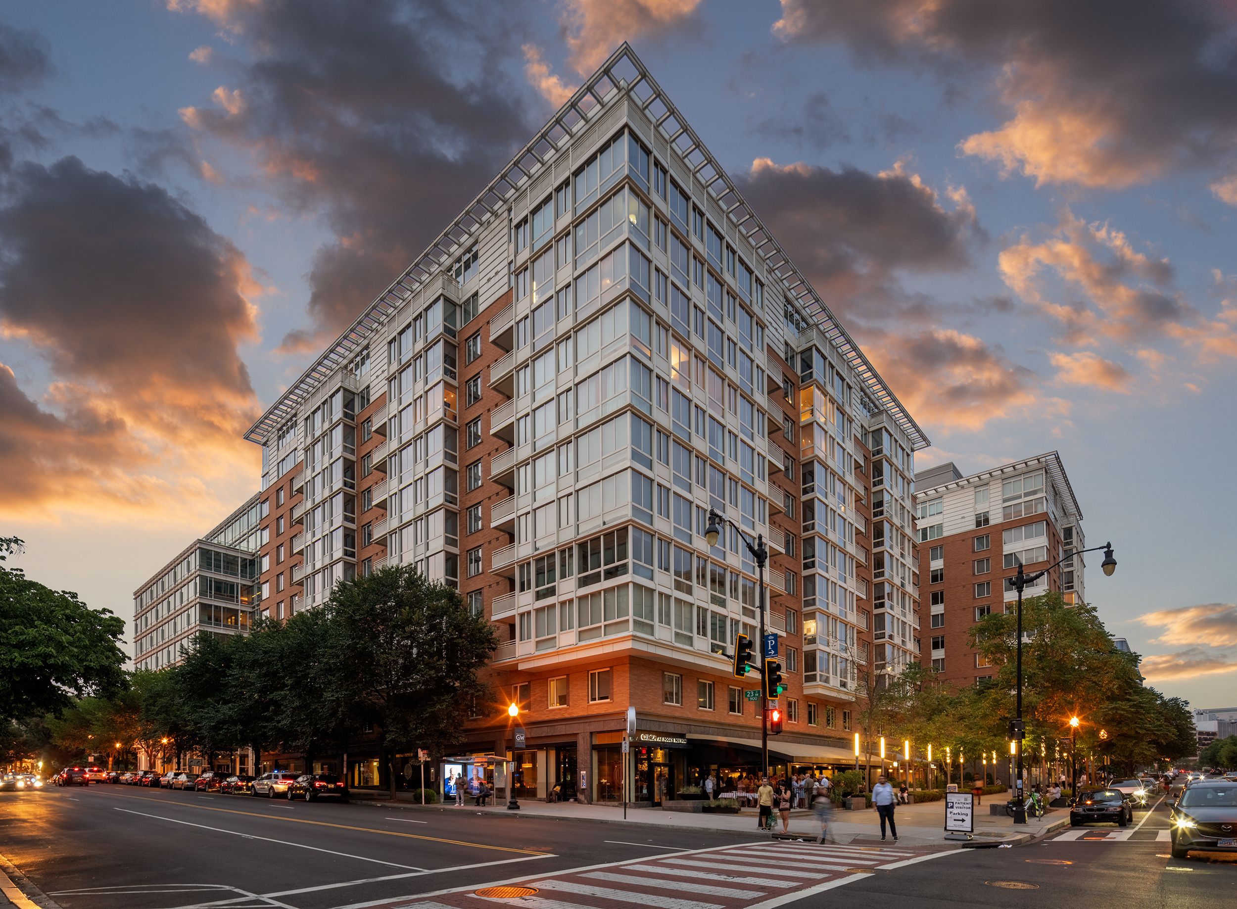 Modern building at sunset with clouds and traffic in the foreground.