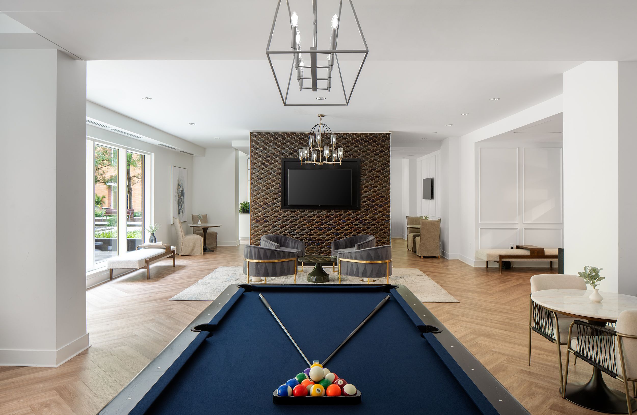 Modern game room with a pool table, seating area, and large windows.