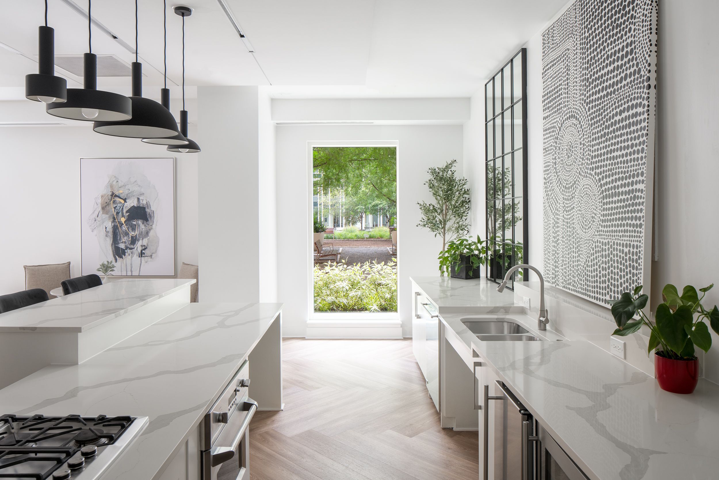 Modern kitchen with white cabinetry, a large window, and greenery visible outside.