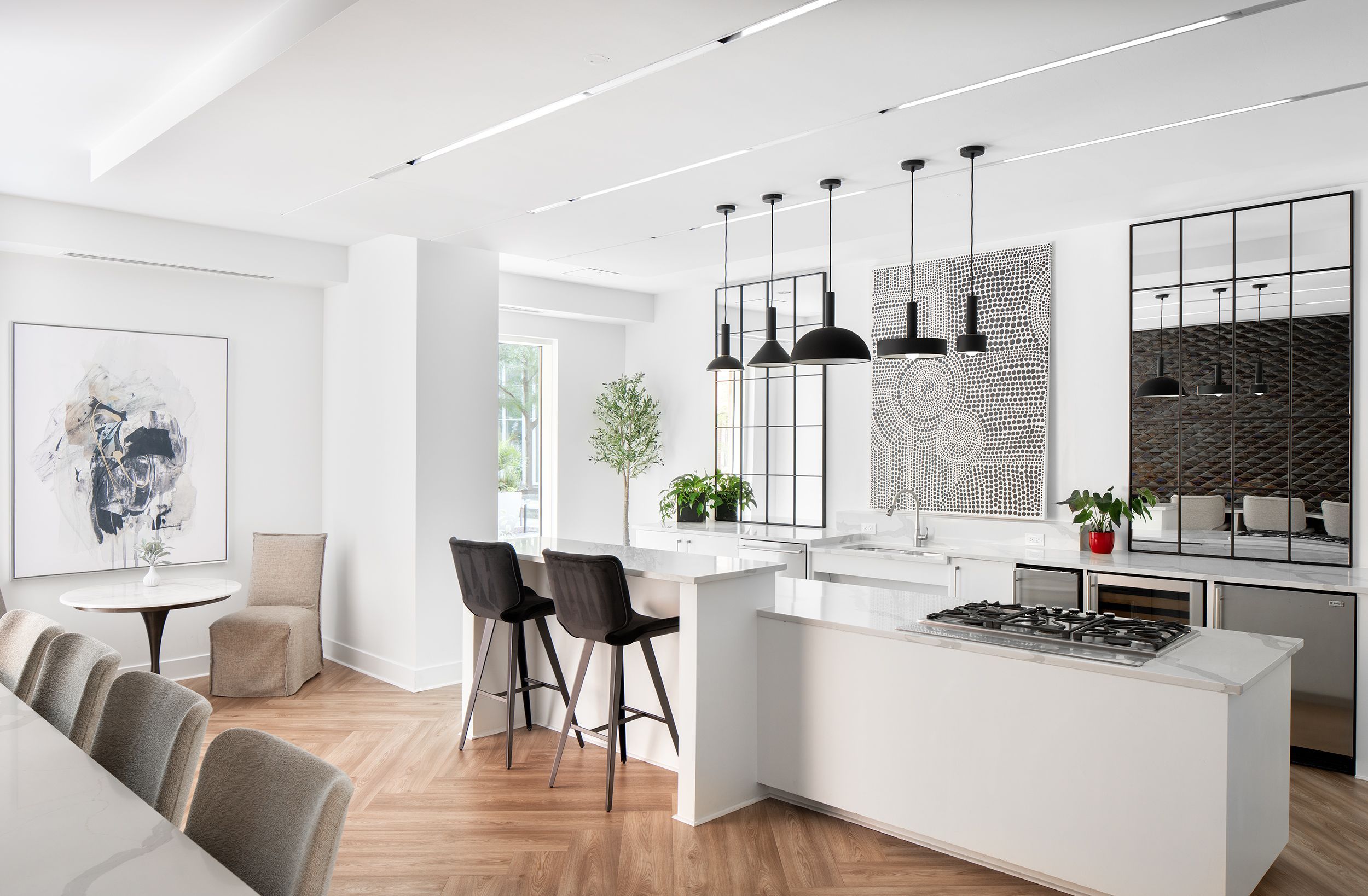 Modern kitchen with white cabinets, wooden flooring, and stylish bar stools.