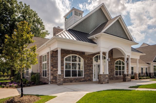 Modern building with stone and siding exterior, featuring multiple windows and a peaked roof.