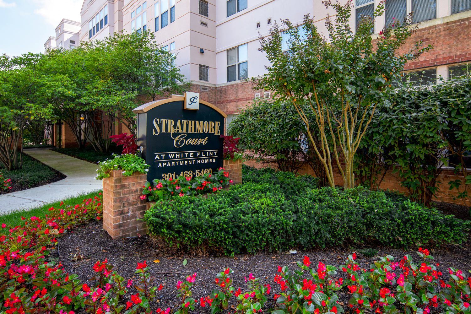 Sign for Stratford Court surrounded by colorful flowers and greenery.