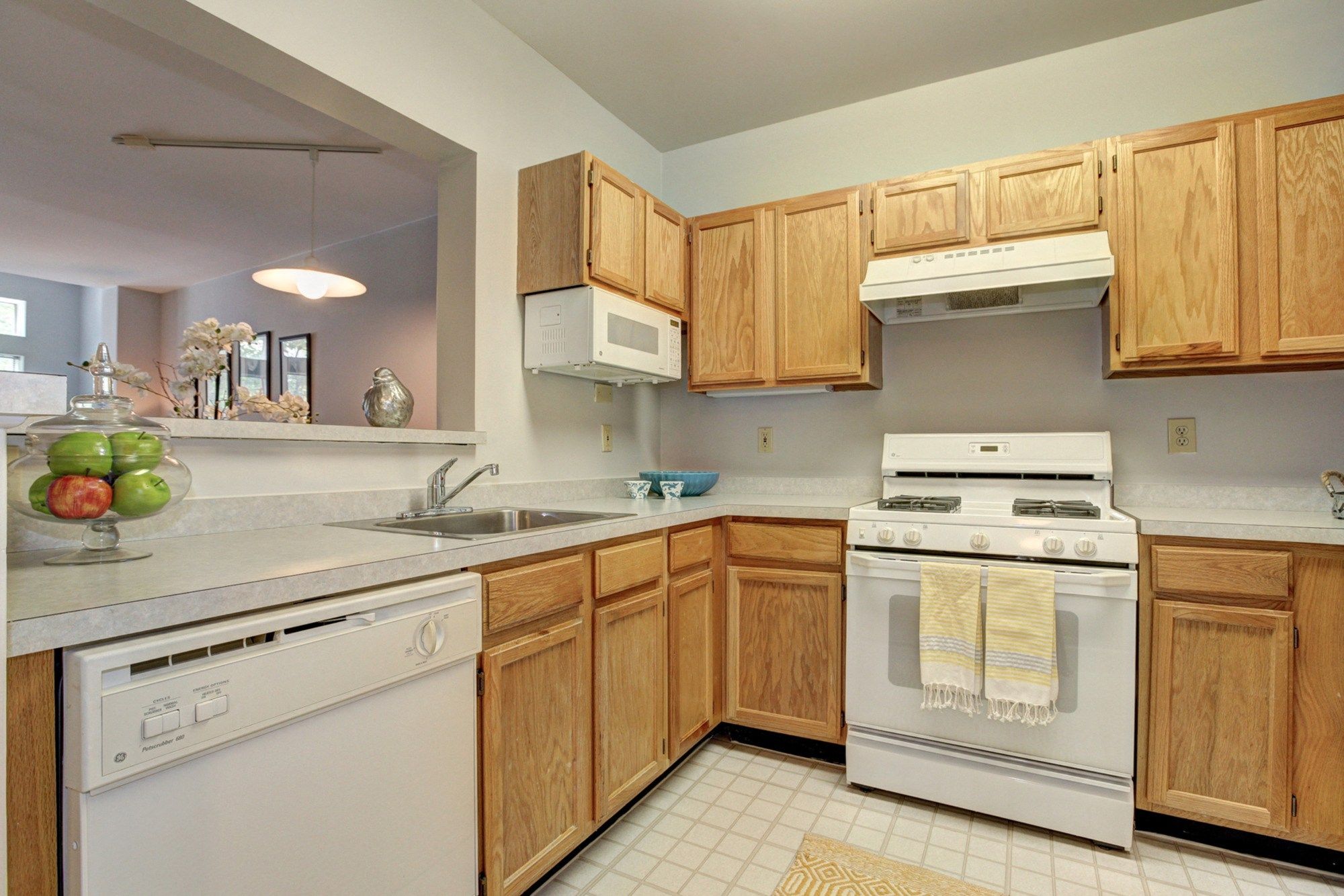 Modern kitchen with wooden cabinets, white appliances, and a sink.