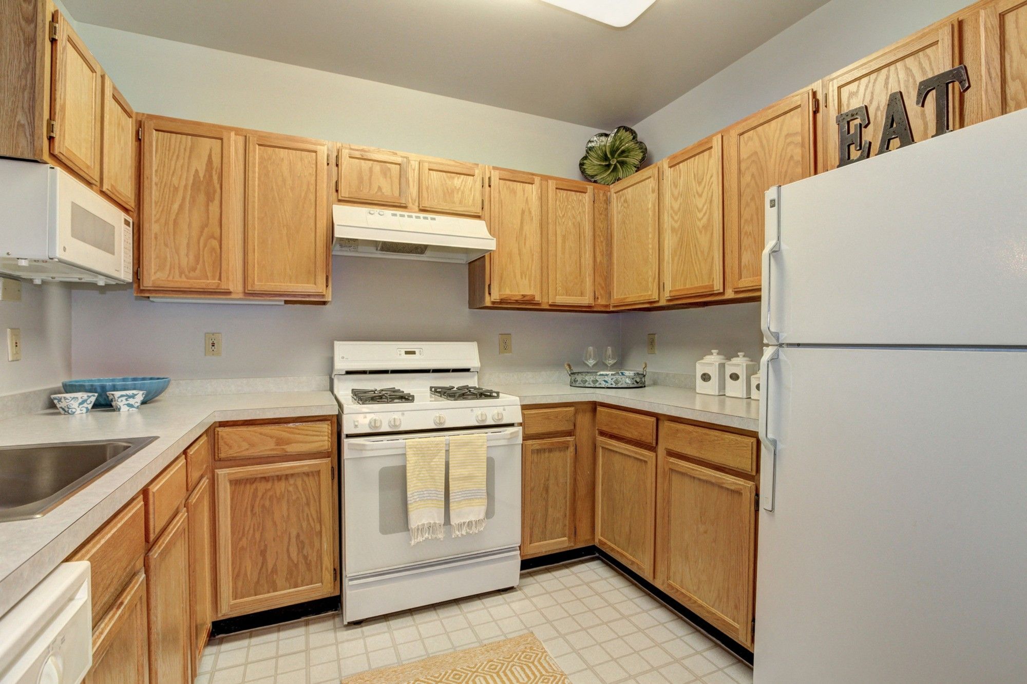 Cozy kitchen with wooden cabinets, white appliances, and a light color scheme.