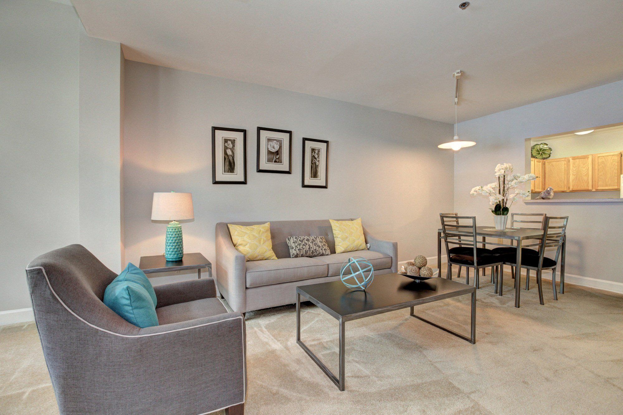 Modern living room with gray sofa, dining area, and light-colored decor.