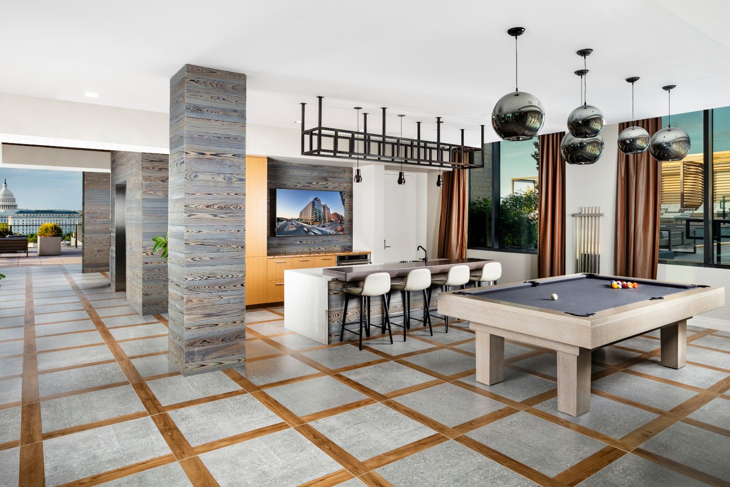 Modern interior with a pool table, bar area, and large windows showcasing a view.