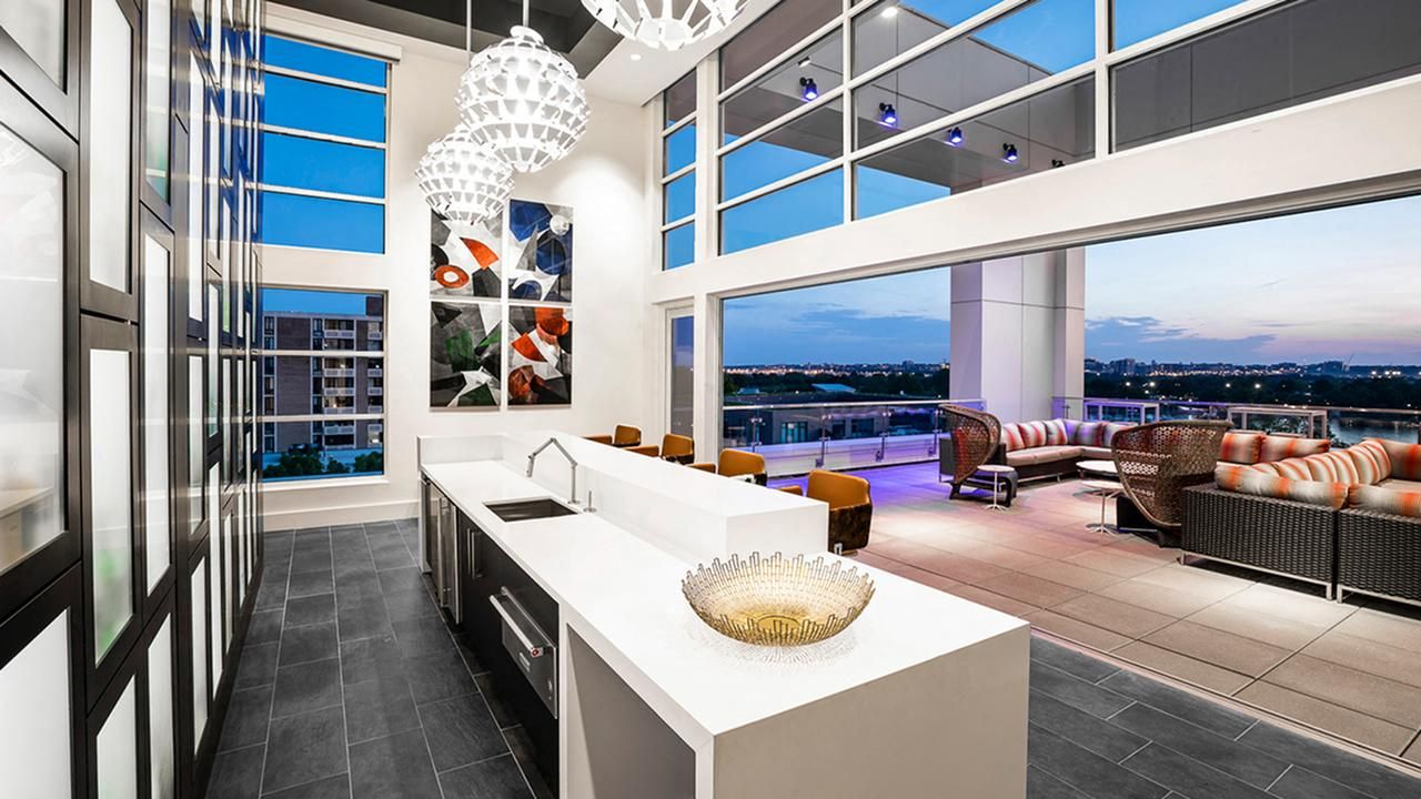 Modern kitchen with large windows, elegant lighting, and open outdoor seating area.
