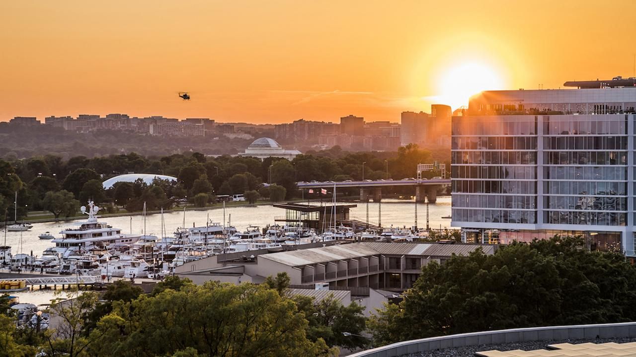 Sunset over a marina with boats and modern buildings.