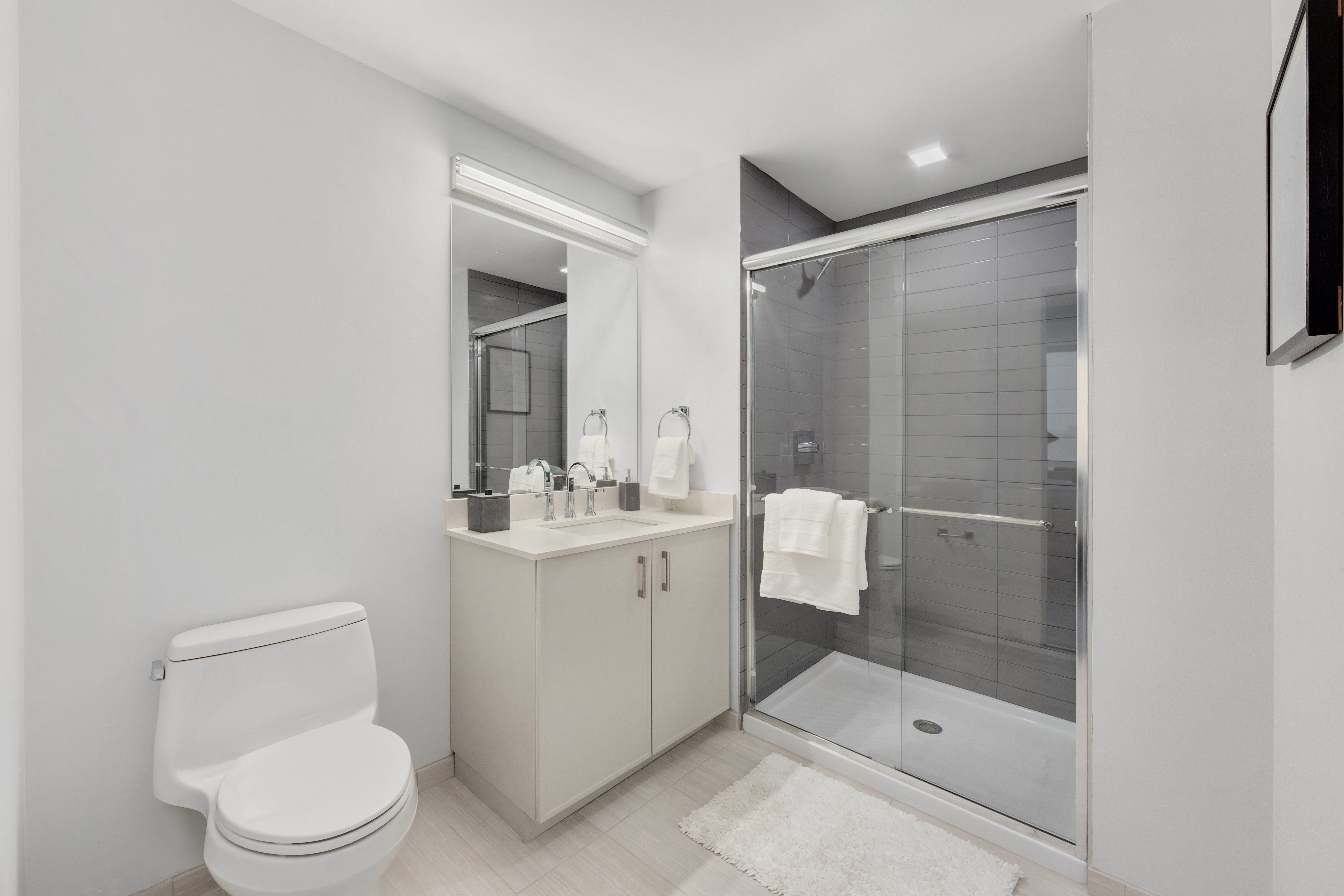 Modern bathroom with a shower, sink, and toilet in a minimalist design.