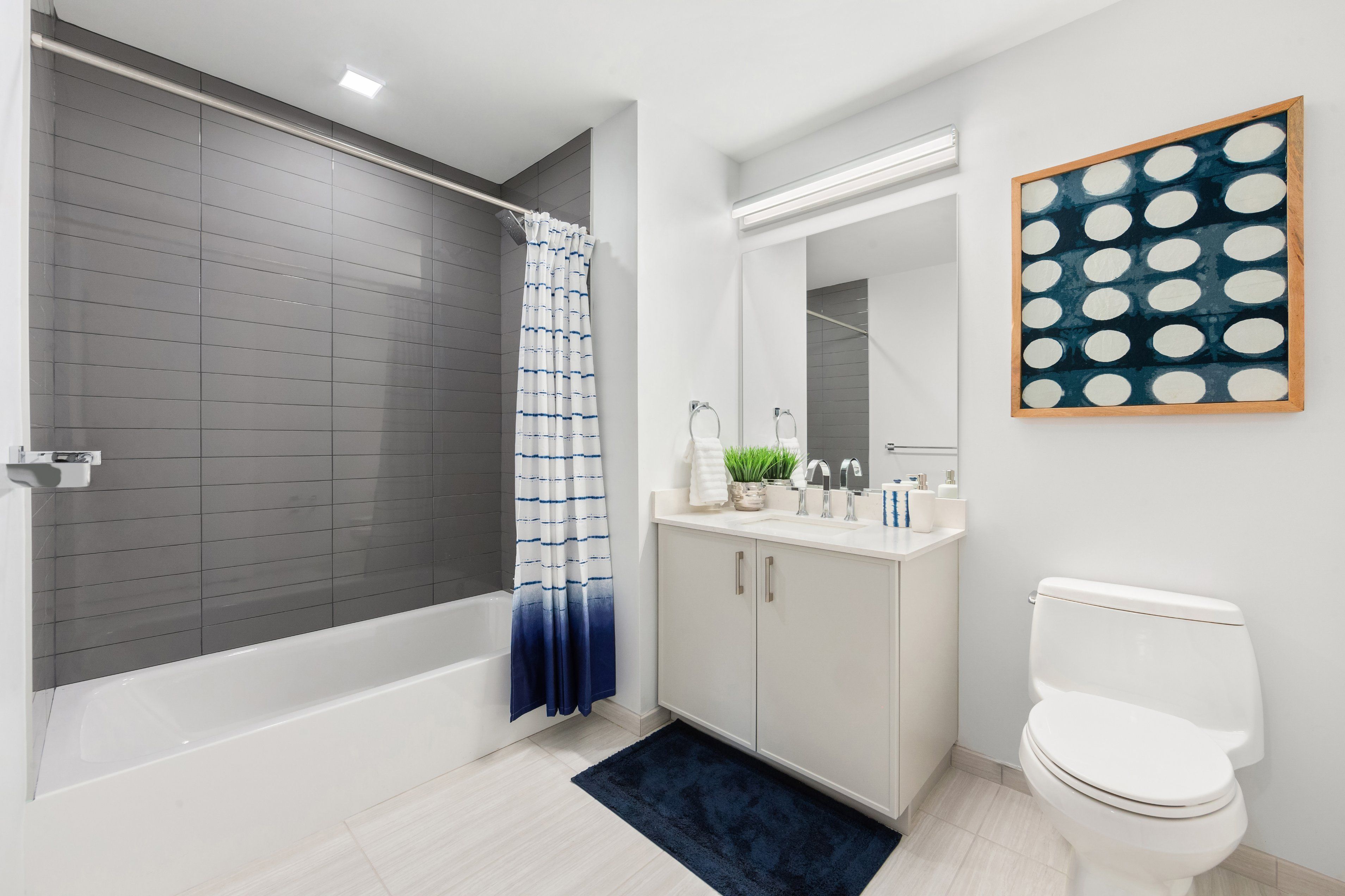 Modern bathroom featuring a bathtub, sink vanity, and a toilet with simple decor.