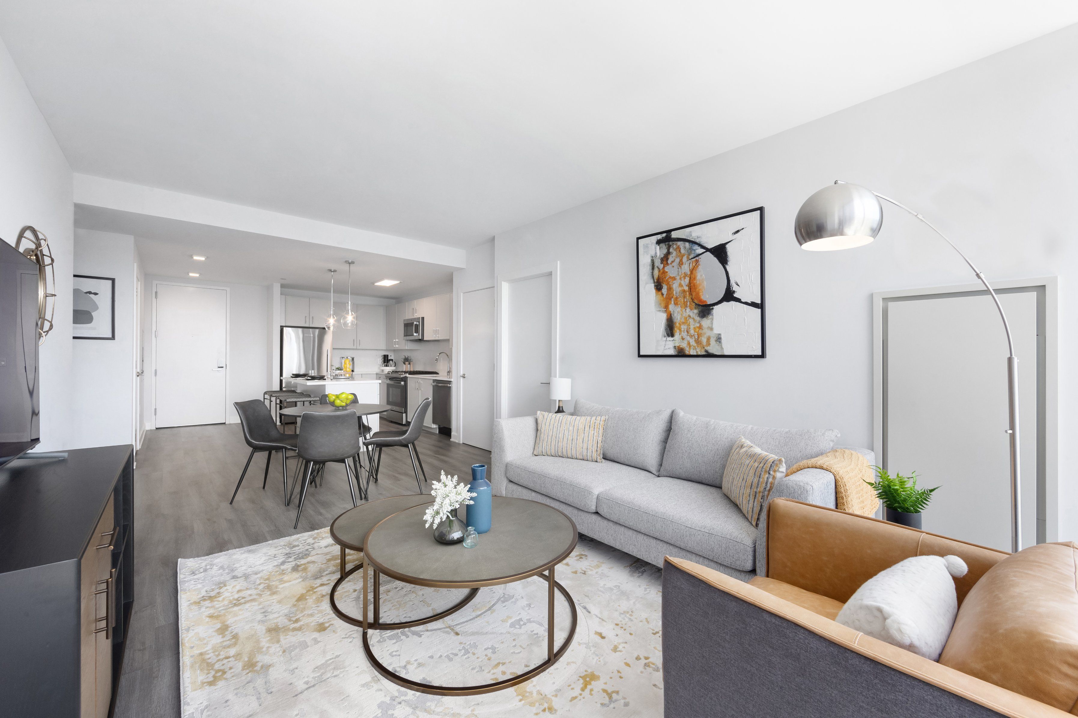 Modern living room with a couch, round coffee table, and dining area in the background.