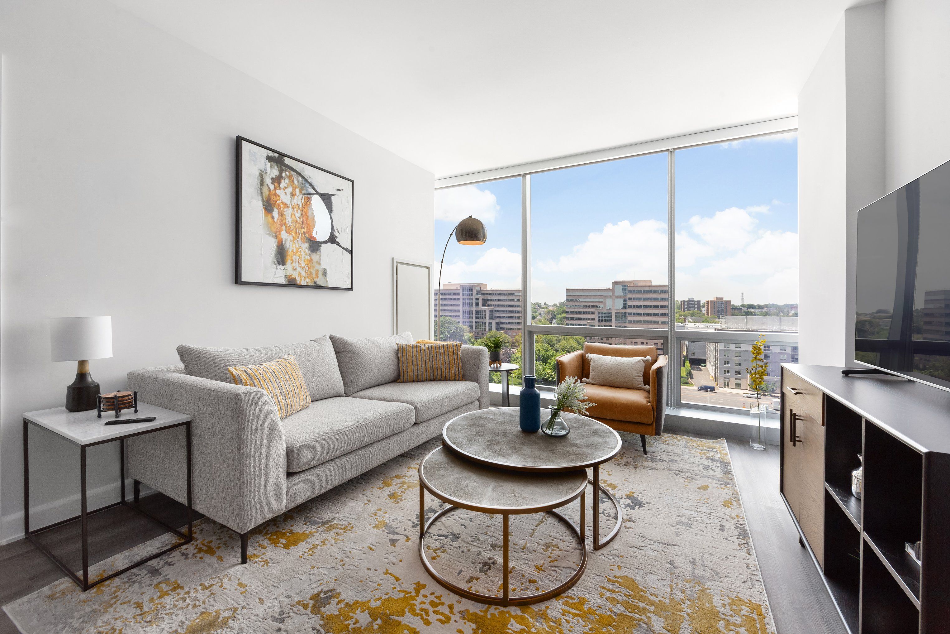 Modern living room with large window, sofa, armchair, and round coffee table.