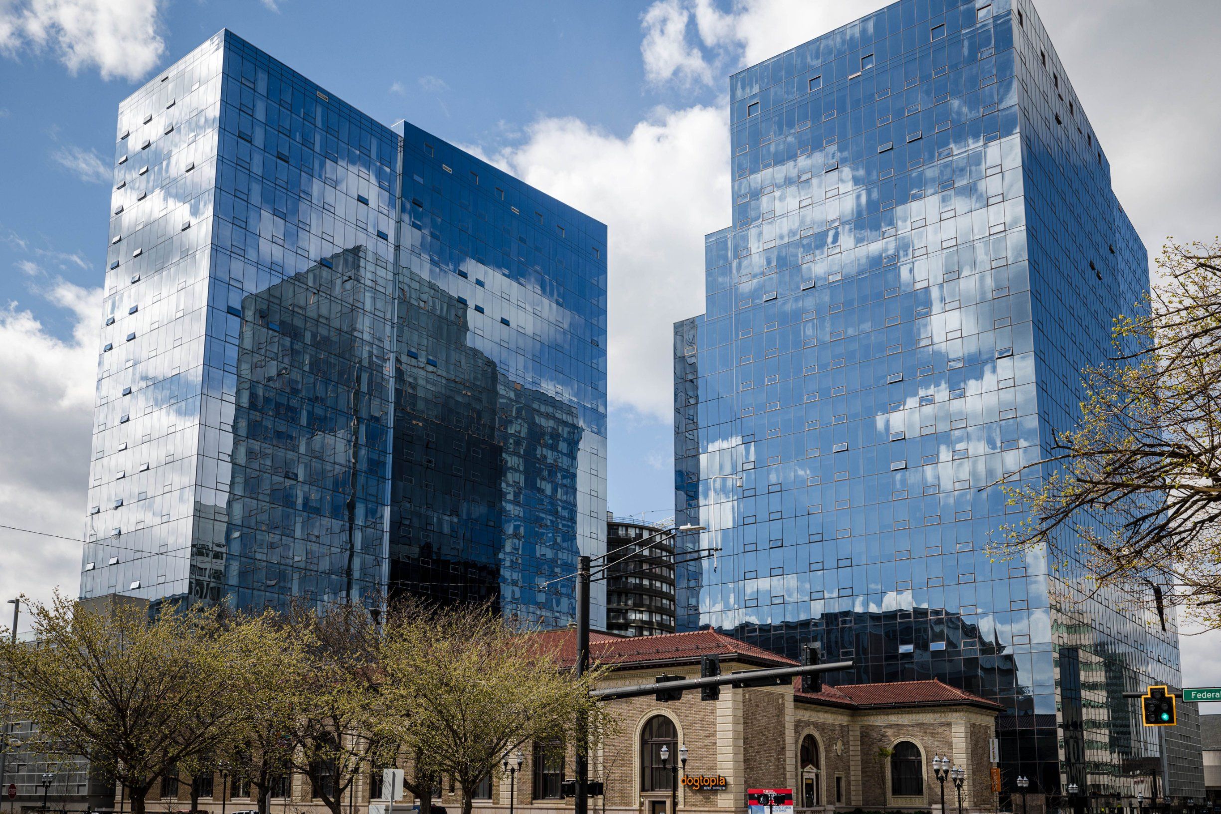 Two modern glass skyscrapers reflect clouds beside a historic building.