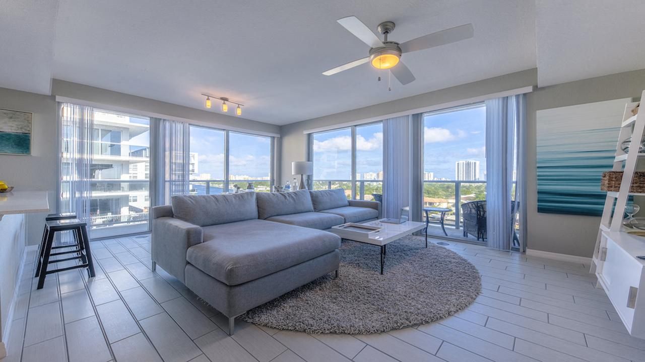 Modern living room with large windows, gray sofa, and scenic city view.