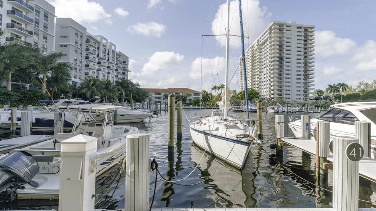 Marina with boats and tall buildings under a partly cloudy sky.
