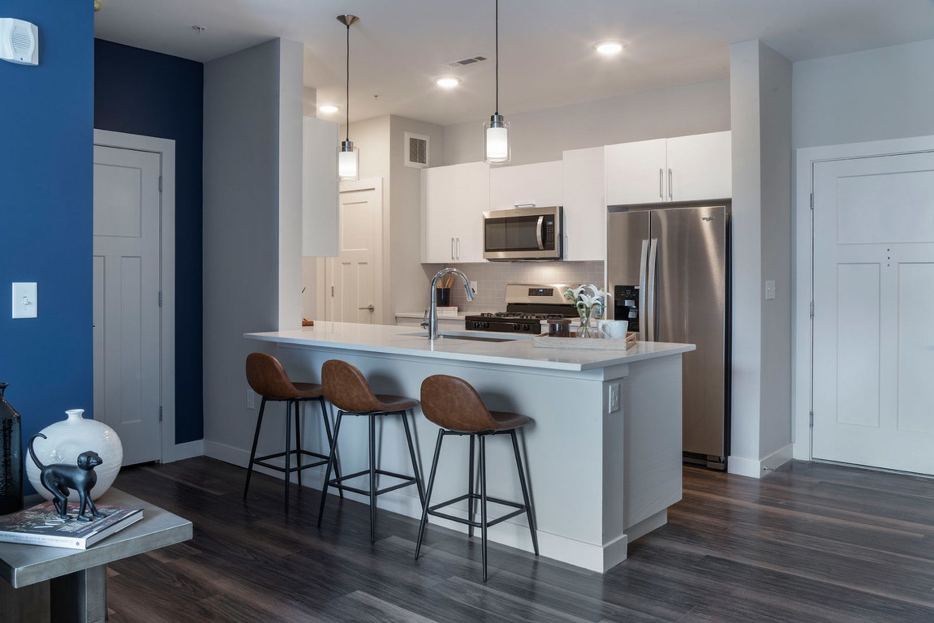 Modern kitchen with bar stools, white cabinetry, and stainless steel appliances.