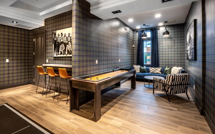 Modern game room with plaid walls, shuffleboard table, and cozy seating area.