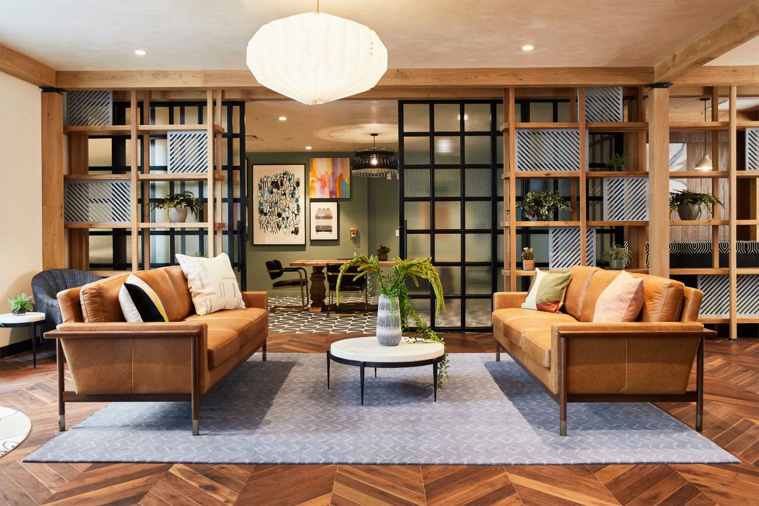 Modern living room with two brown sofas, a round table, and wooden shelving.