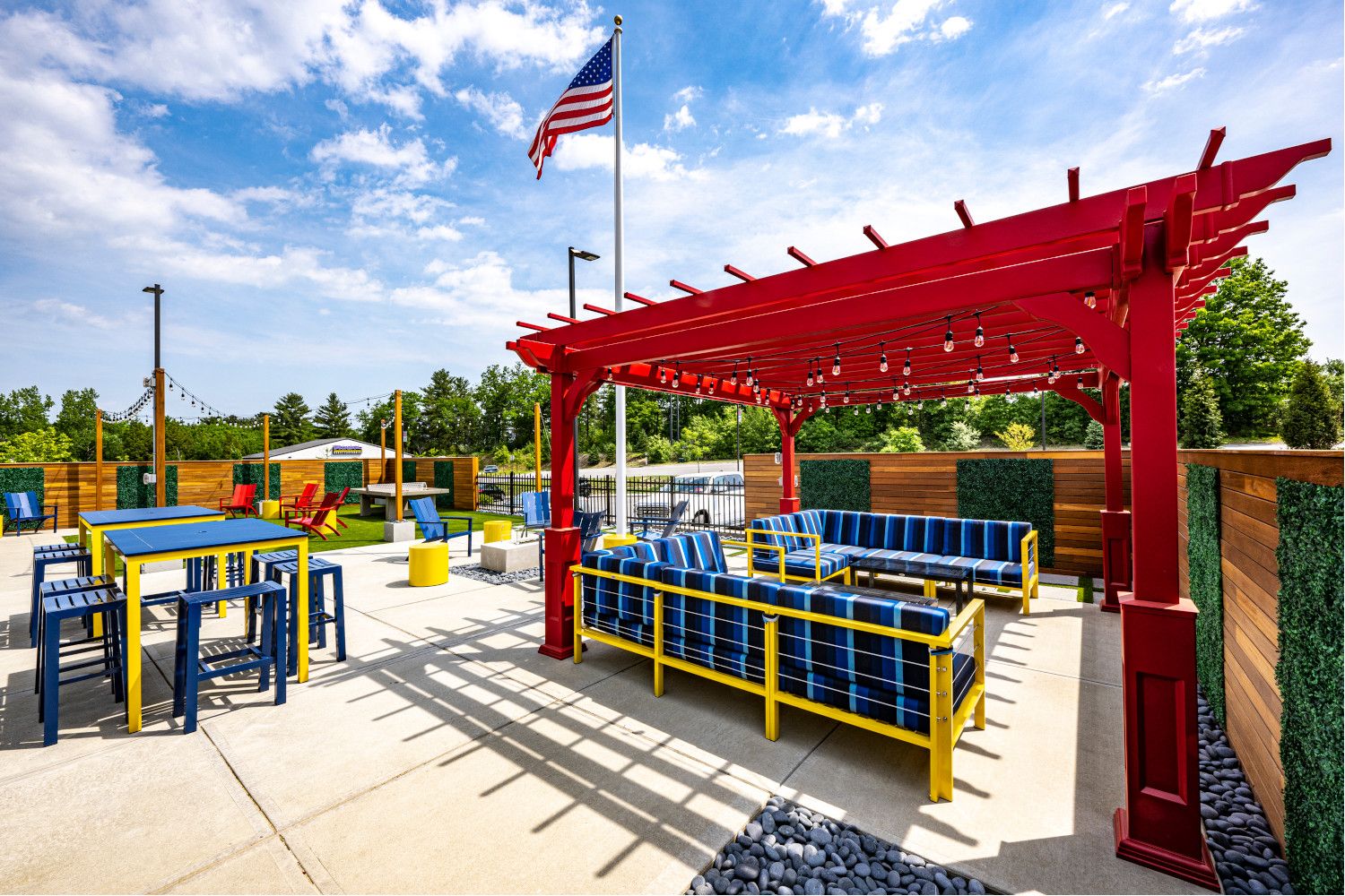 Colorful outdoor seating area with a pergola and American flag against a blue sky.