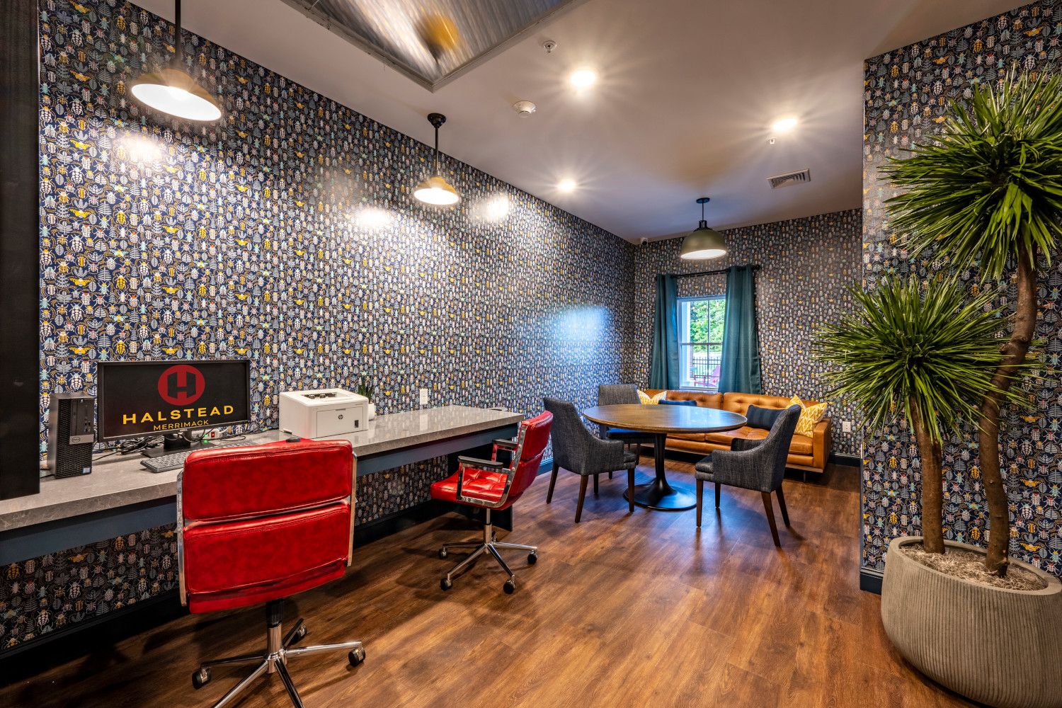 Modern office space with a desk, seating area, and decorative plants.