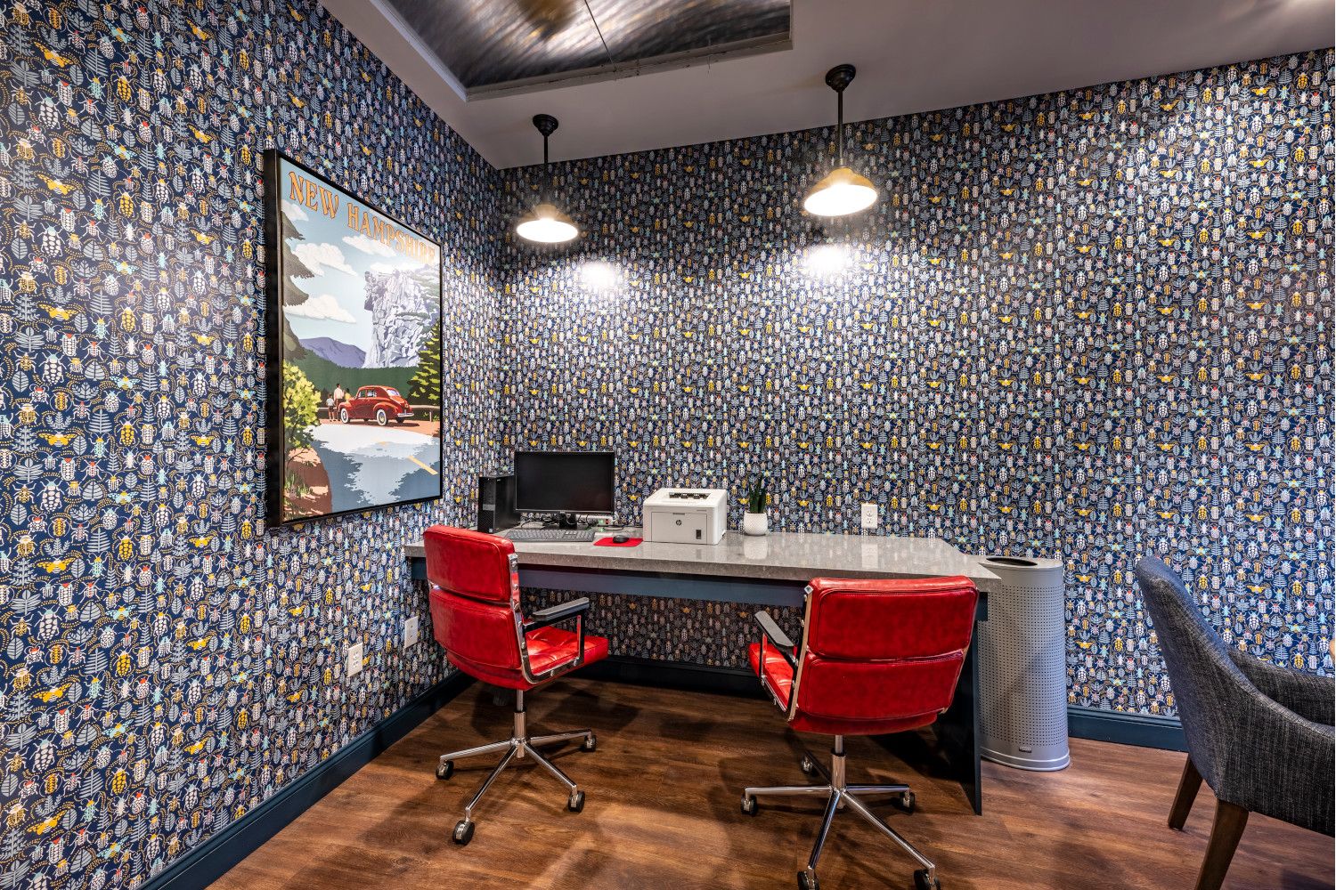Modern office with a patterned wall, red chairs, and a computer desk.