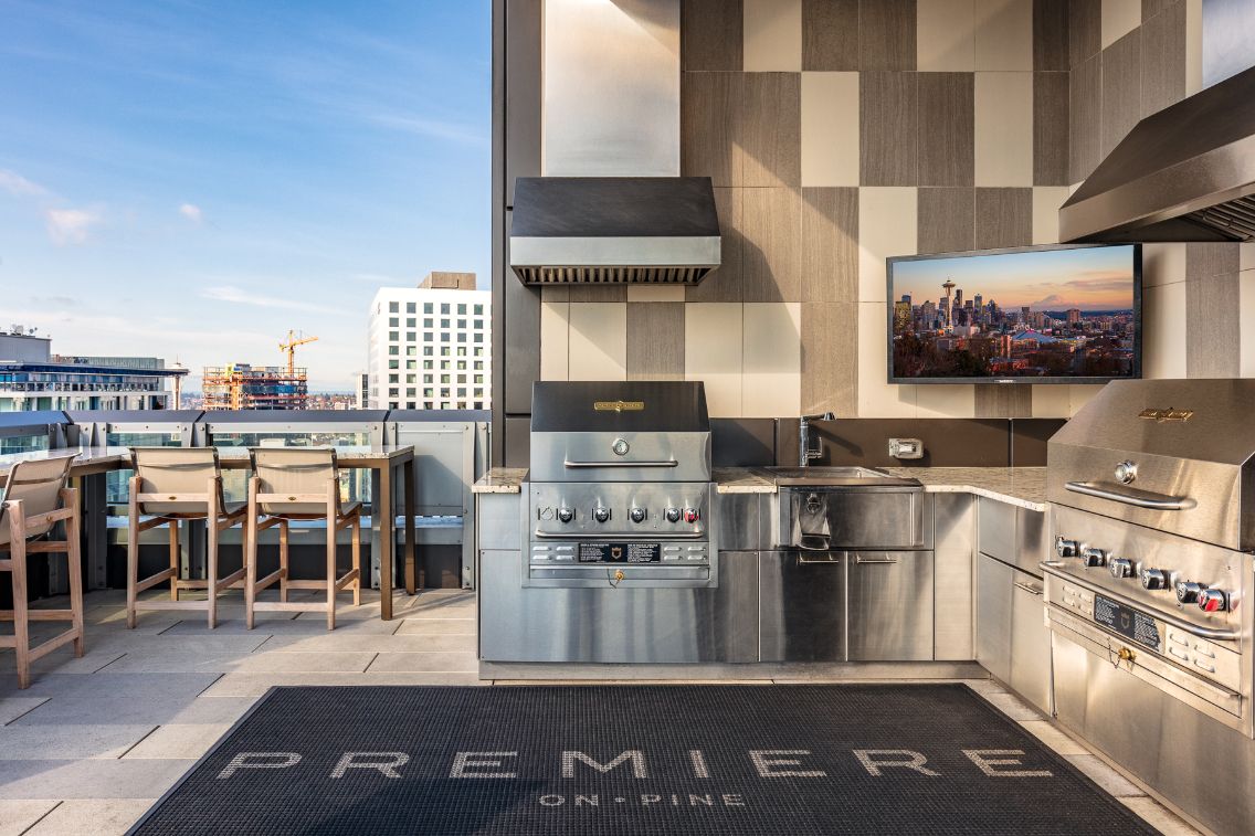 Modern open-air kitchen with stainless steel appliances and a view of the city skyline.