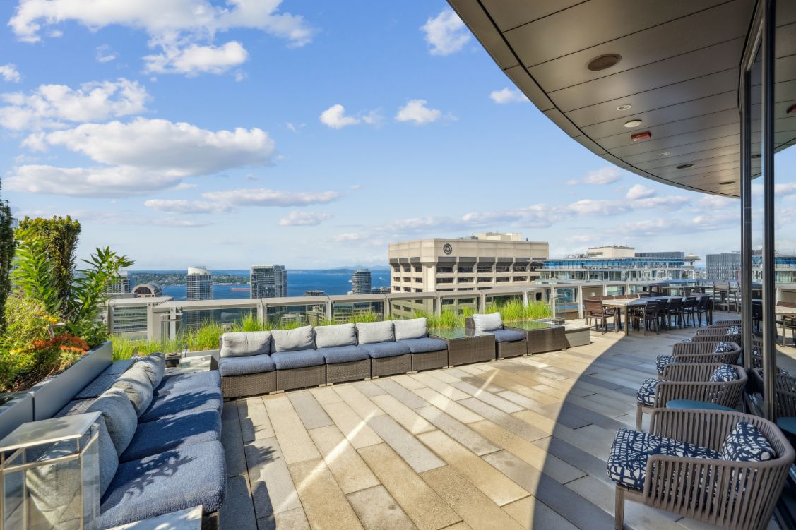 Rooftop lounge area with seating and ocean view under a partly cloudy sky.
